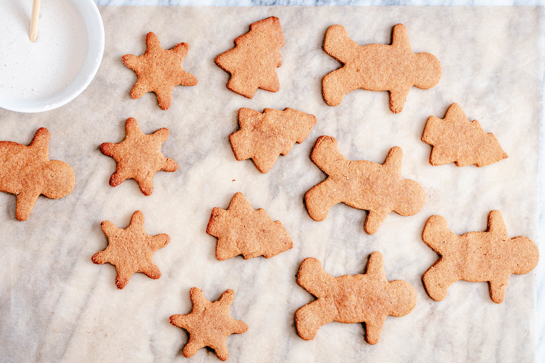 vegan gingerbread cookies vegan gingerbread cookies cooling on a countertop with small bowl of icing
