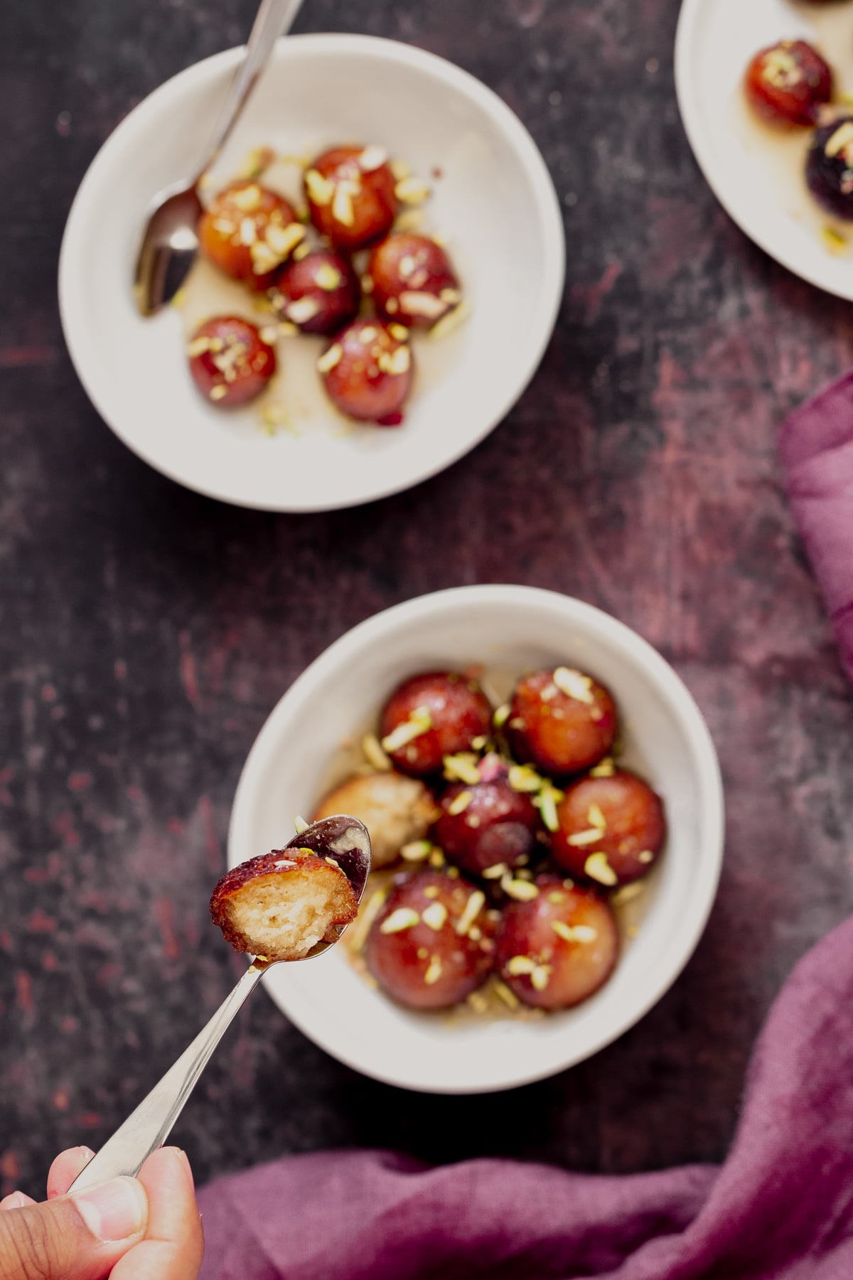vegan gulab jamun a small spoon with half a syrup soaked vegan Indian donut