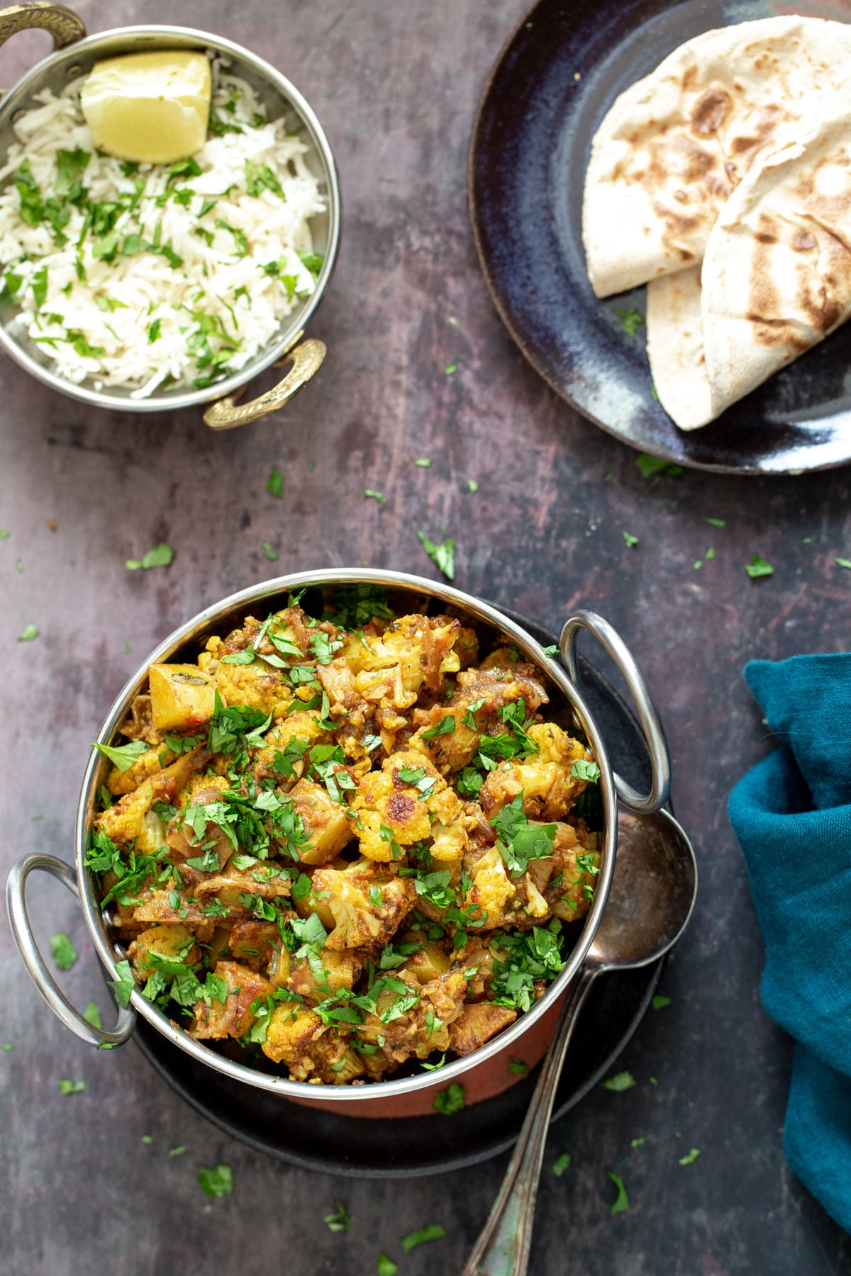 vegan aloo gobi a bowl of vegan aloo gobi next to a small dish with rice and some flatbread