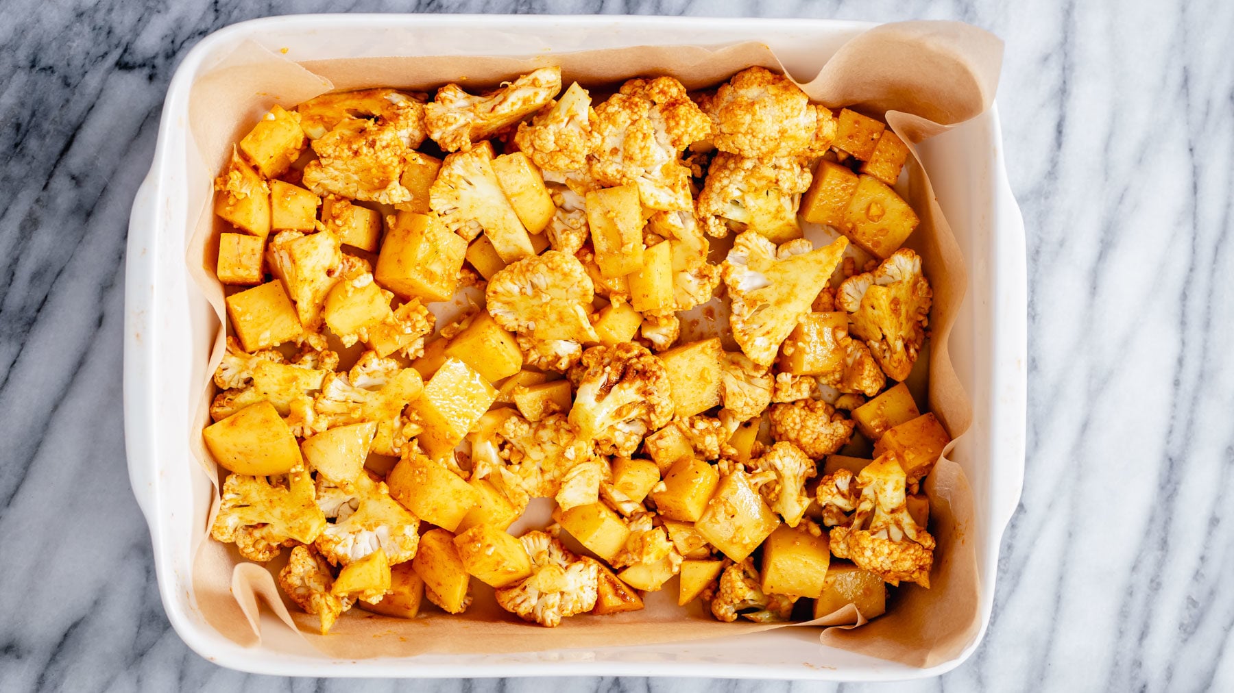vegan aloo gobi cauliflower and potato cubes in a casserole dish