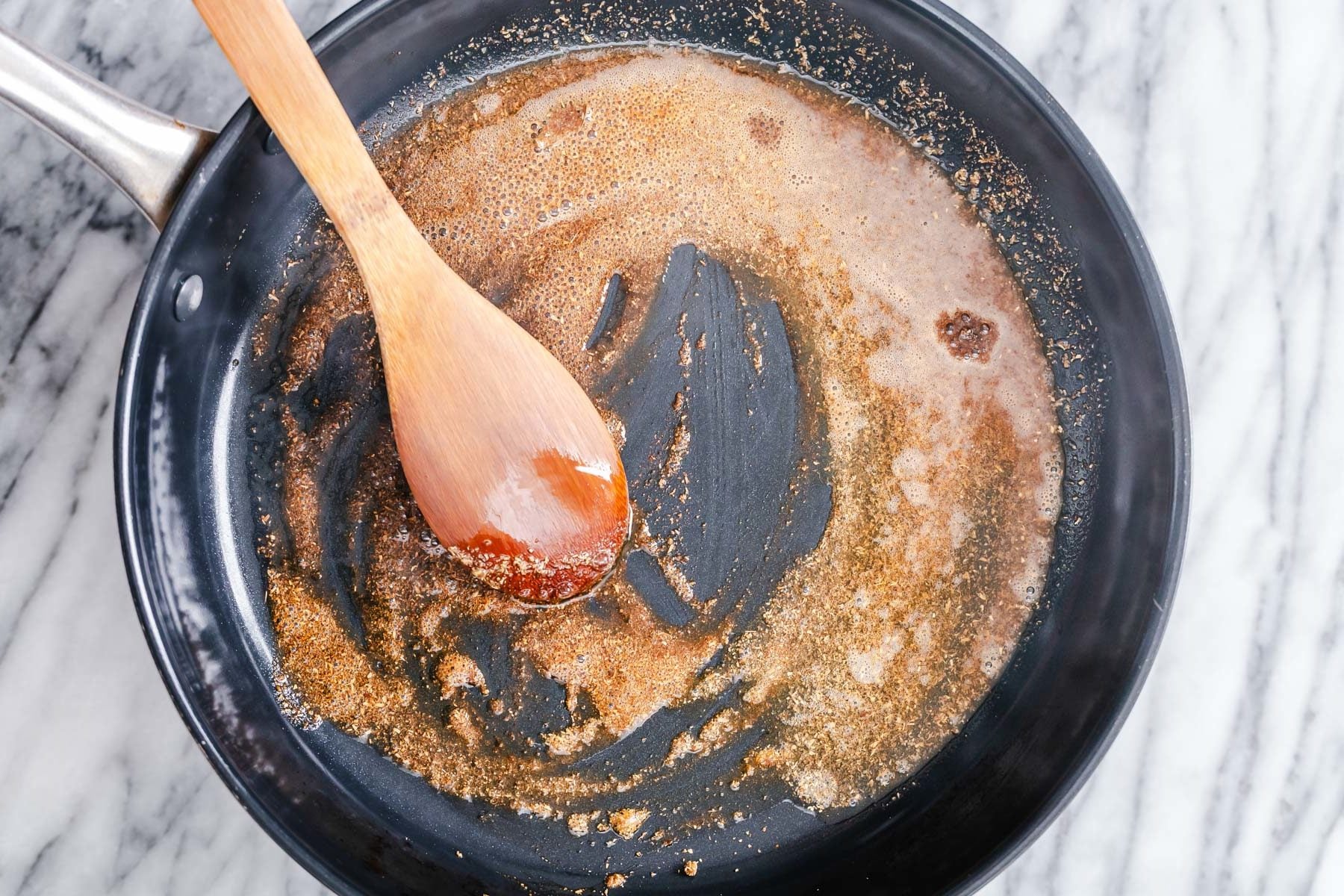 vegan aloo gobi Indian spices being tempered in a black frying pan