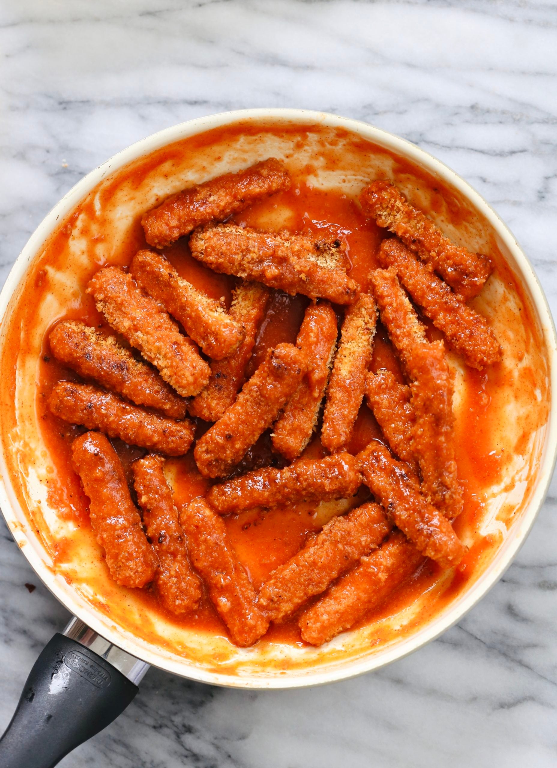 overhead shot of a skillet with vegan baked firecracker tofu wings tossed firecracker sauce