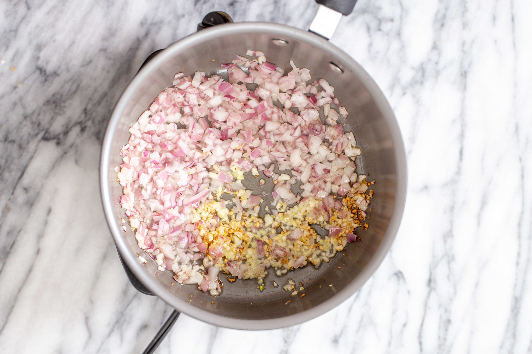 chopped onion, garlic and chile flakes being fried in a pot