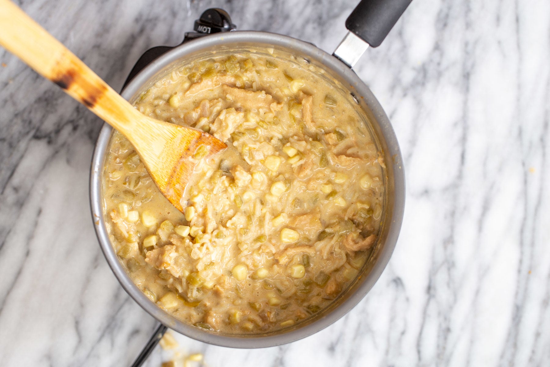 a pot of creamy vegan enchilada soup with a wooden spoon