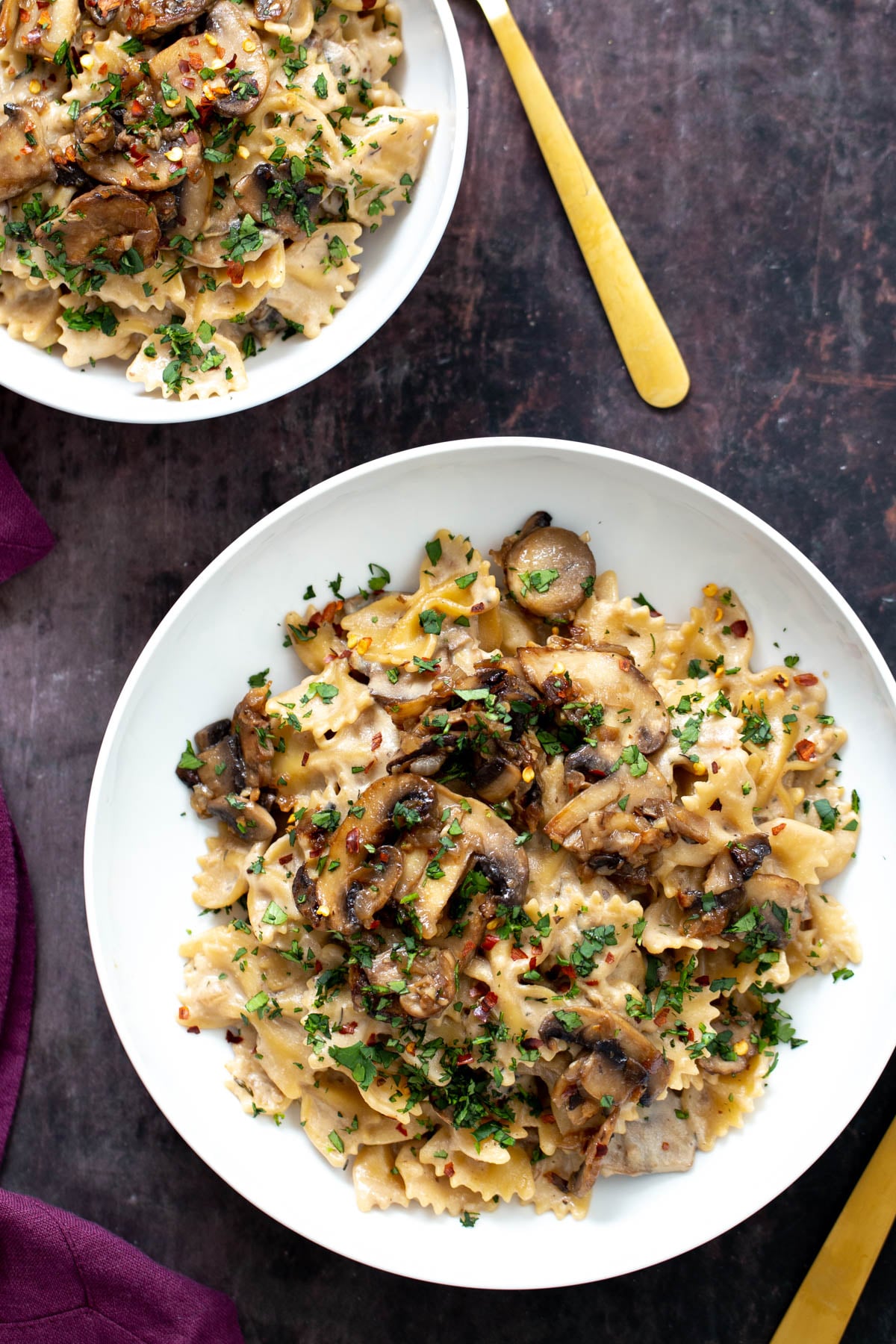 vegan mushroom stroganoff overhead shot of two plates of vegan mushroom stroganoff served on farfalle topped with chopped parsley