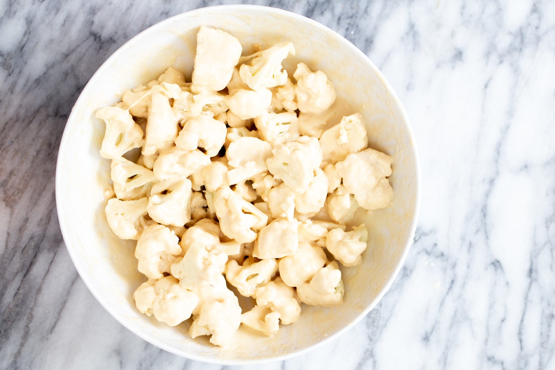 cauliflower being tossed in rice flour for making general tso cauliflower