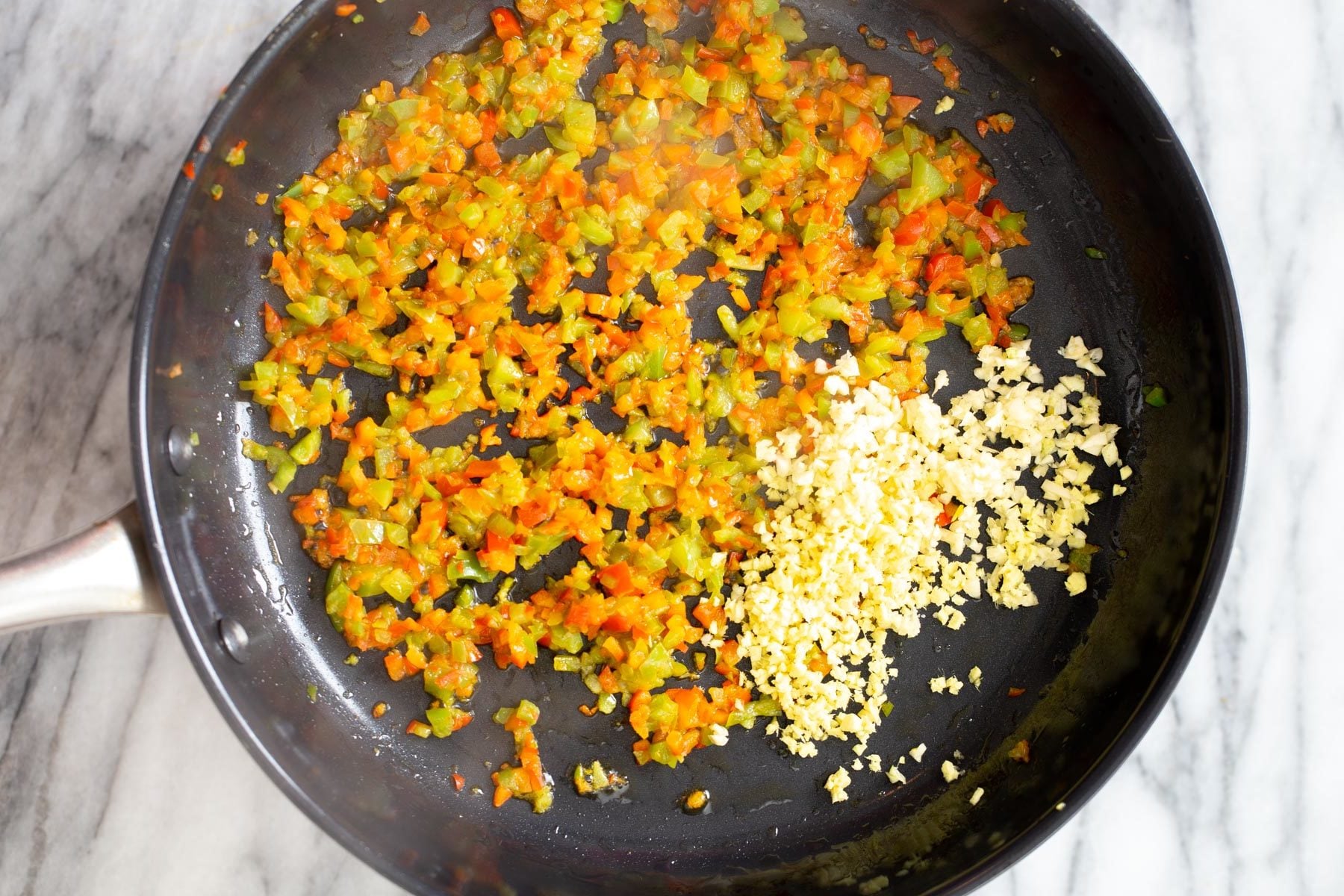 minced garlic being added to frying pan
