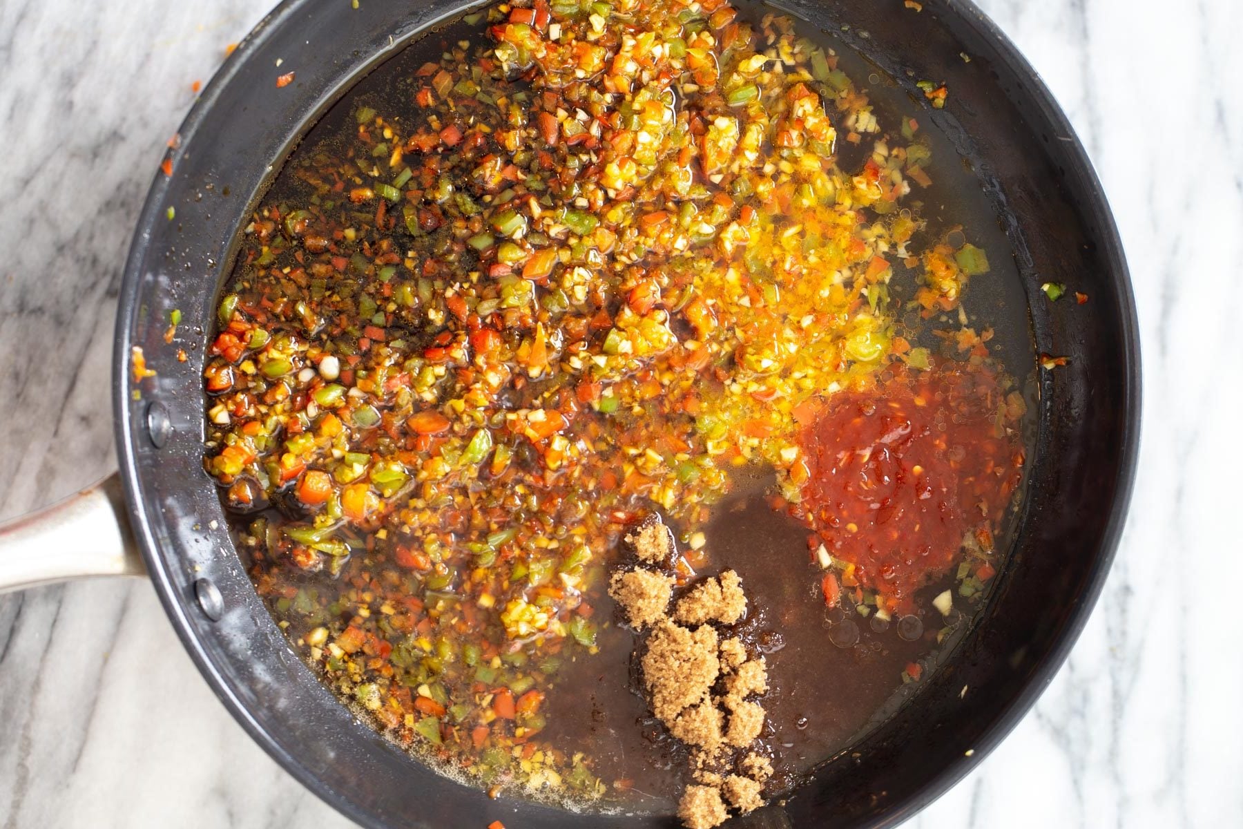 chili sauce and soy sauce being added to general tso sauce in skillet