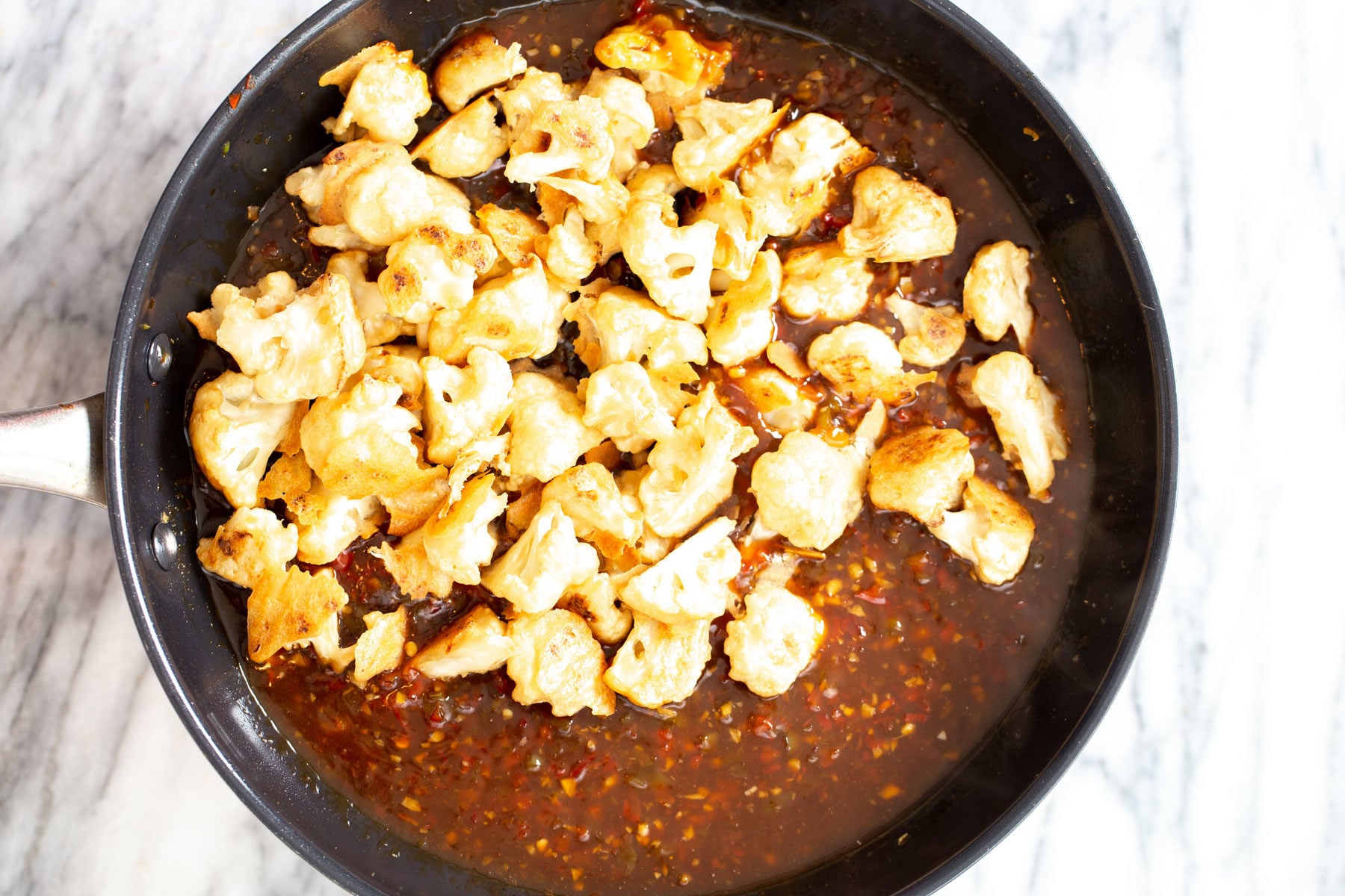 breaded baked cauliflower getting tossed with general tso sauce