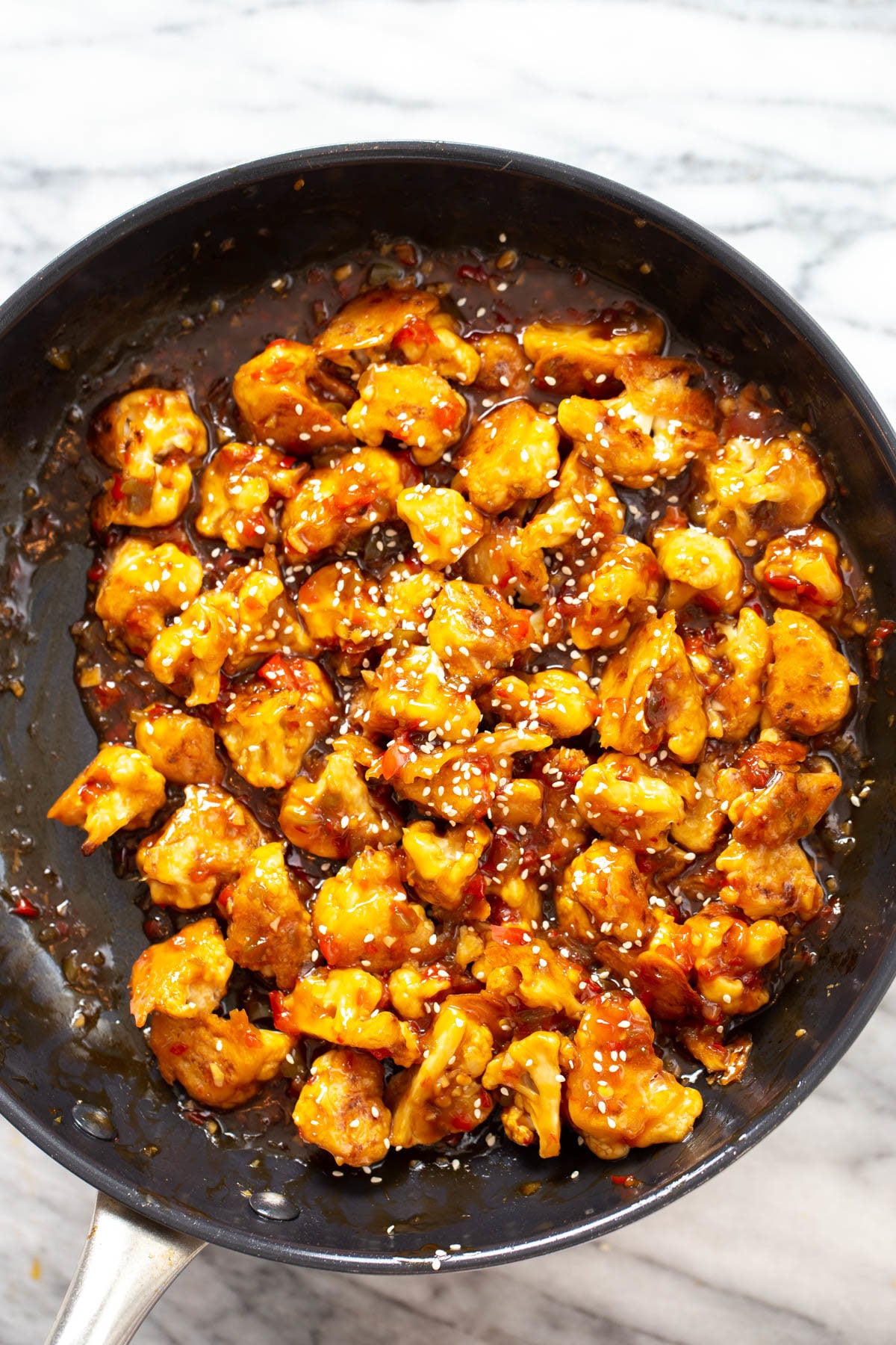 general tso cauliflower being tossed in sweet and sticky sauce