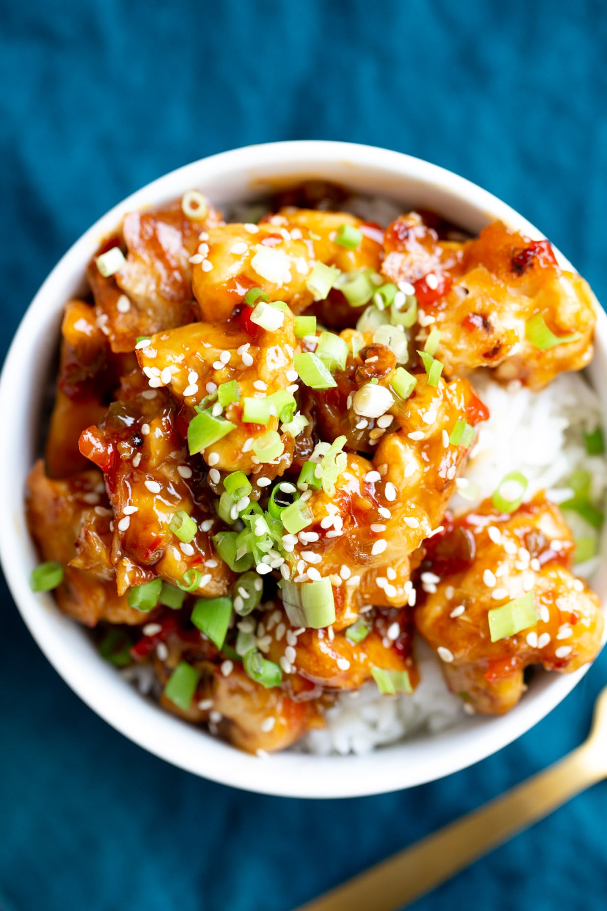vegan baked general tso cauliflower served over rice and sprinkled with sesame seeds