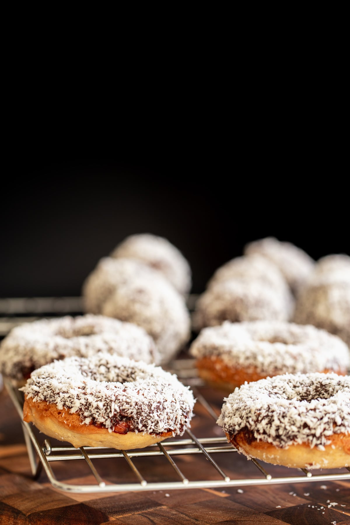 vegan lamington donuts side view of vegan lamington donuts and donuts holes cooling on a cooling rack