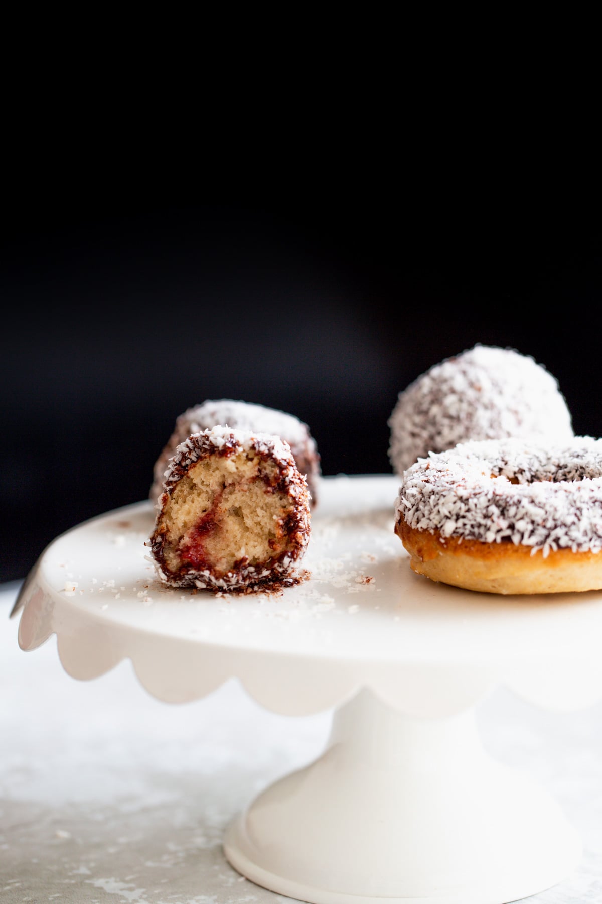 donut holes on a cake stand side view of a vegan lamington donut hole with one bite taken