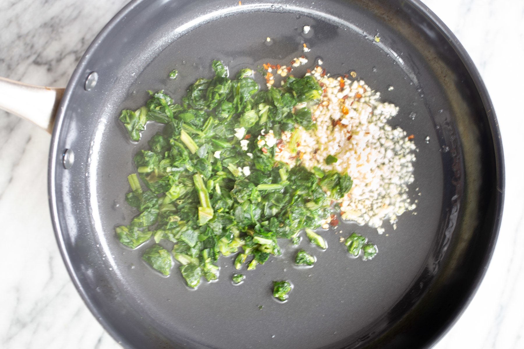 spinach and garlic sauteeing in a frying pan