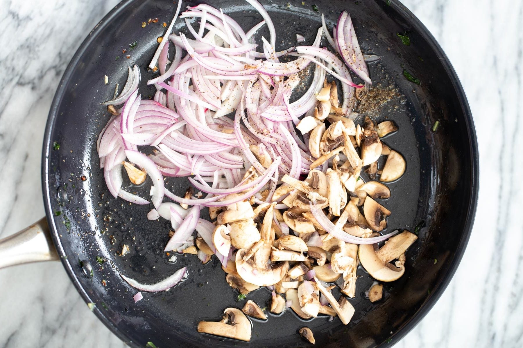 onions and mushrooms being added to a frying pan