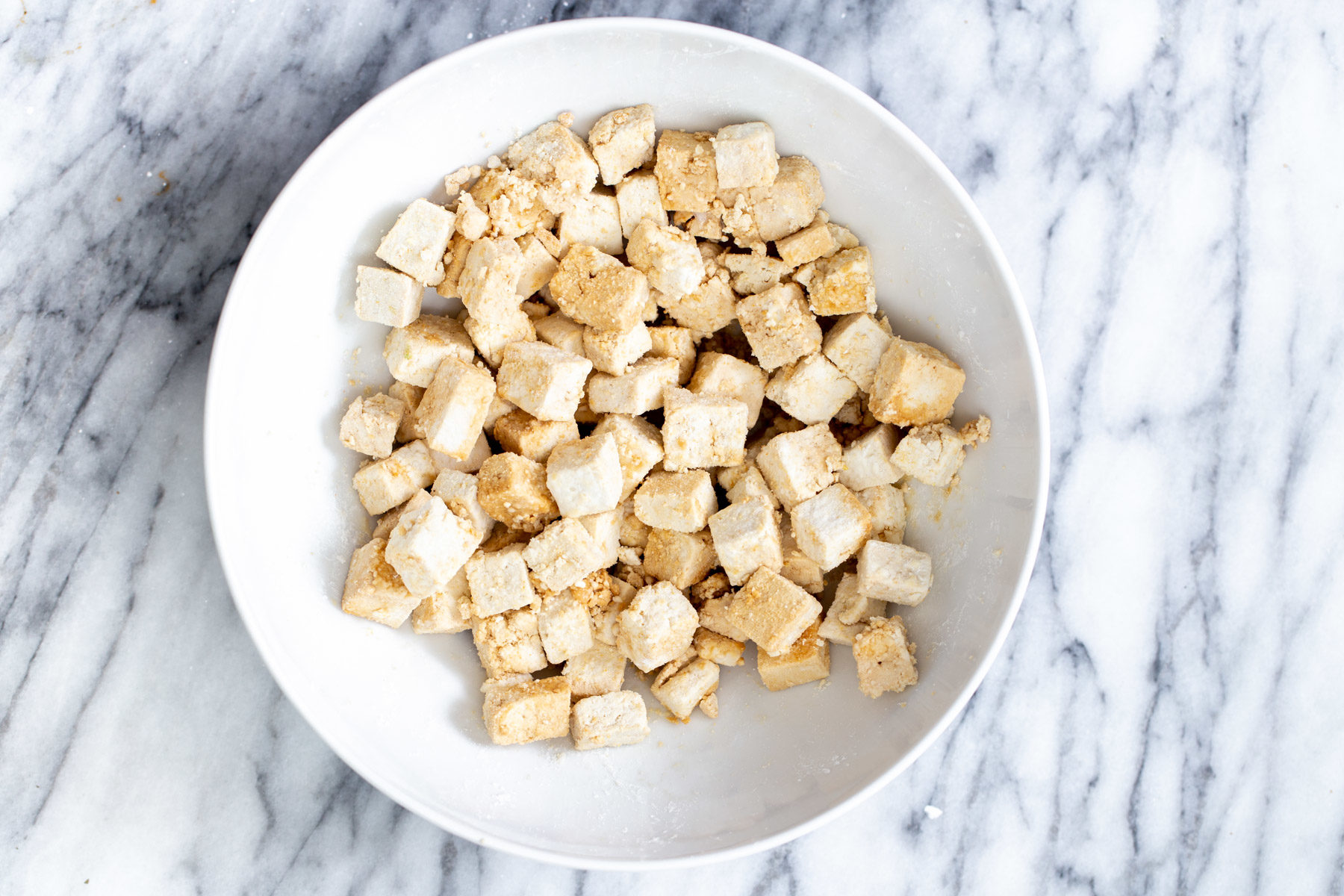 tofu cubes being tossed with soy sauce