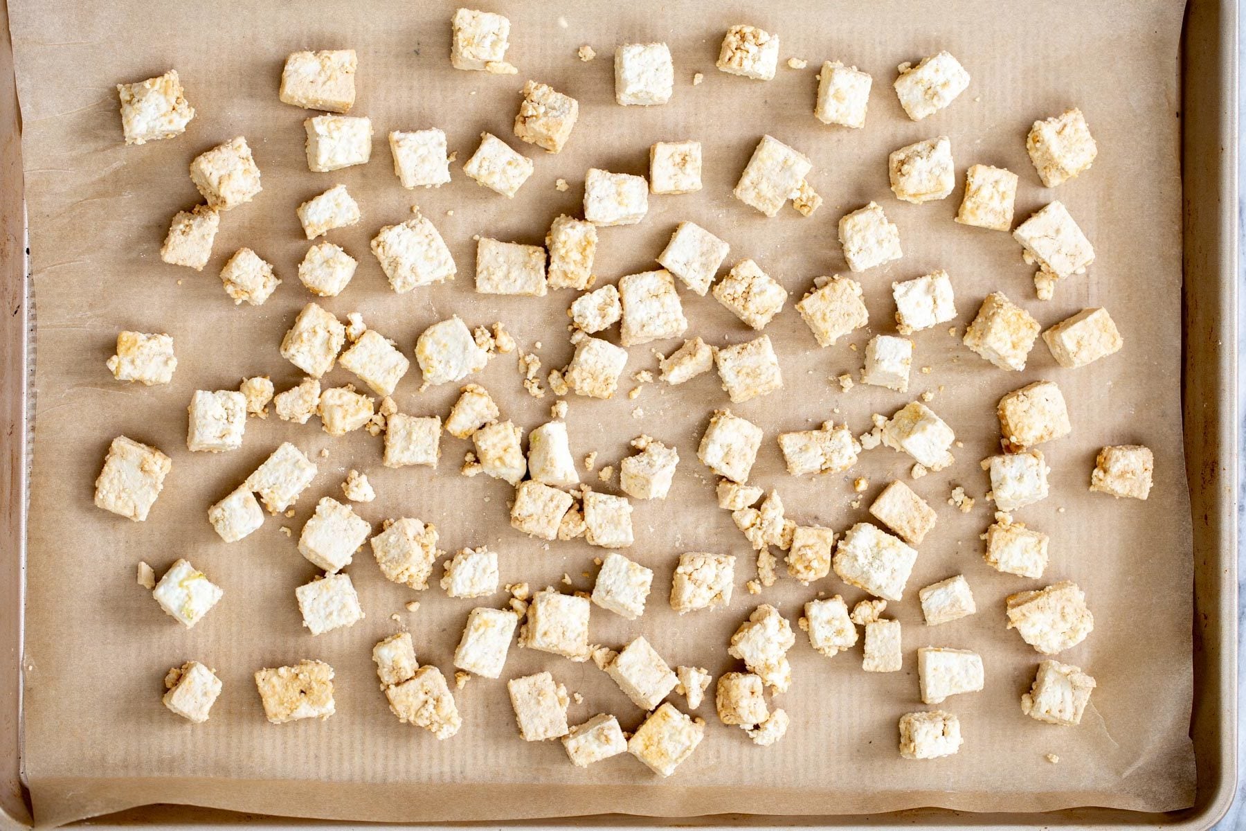 sweet and sour tofu overhead shot of tofu cubes coated in cornstarch on a baking sheet