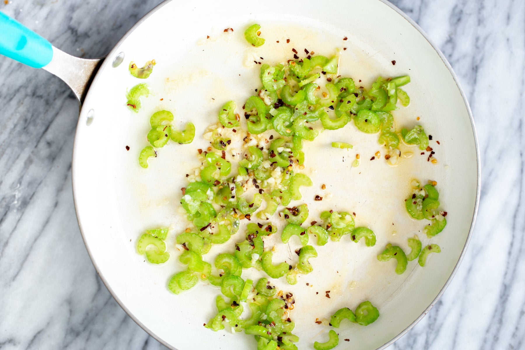 garlic, mustard seeds and sliced celery in a frying pan