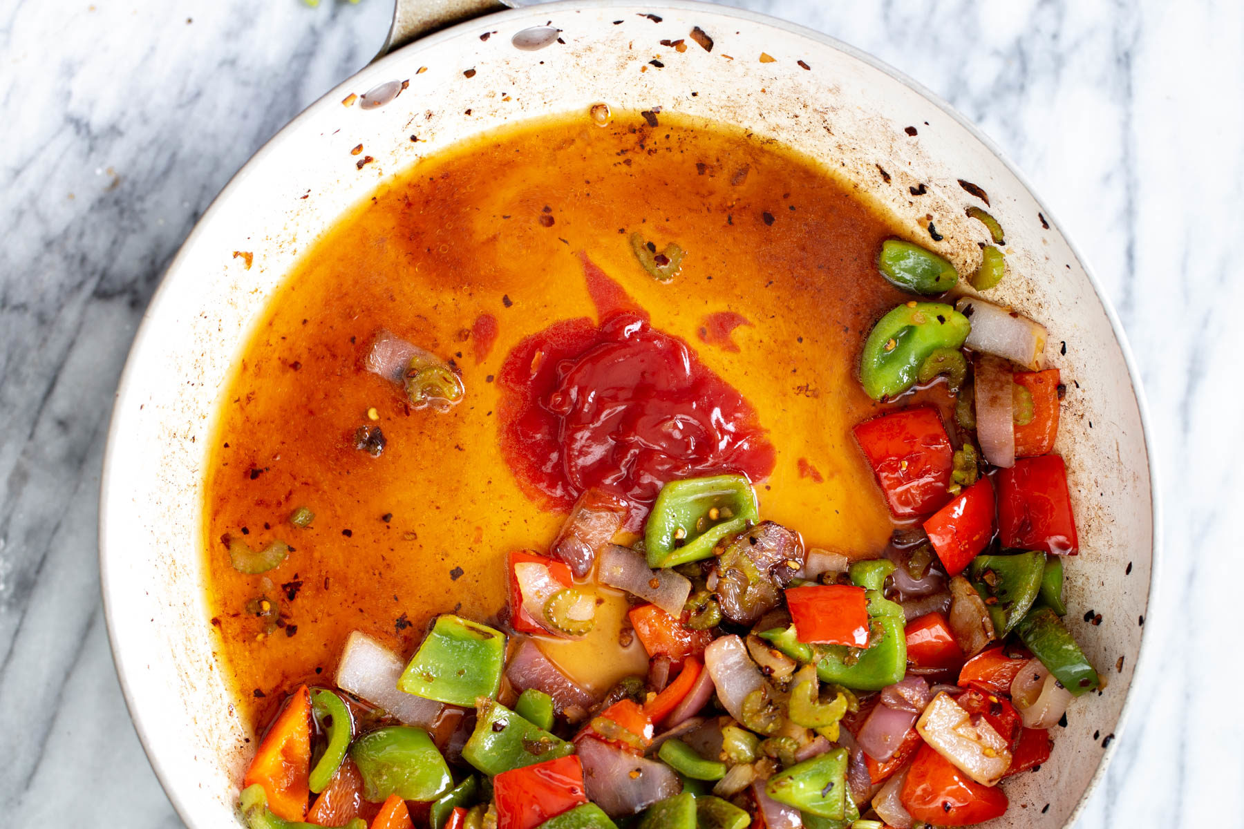 sweet and sour tofu stir-fry sauce being added to a frying pan with vegetables to make sweet and sour tofy