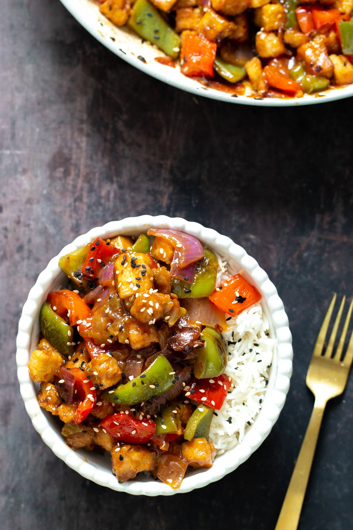 sweet and sour tofu sweet and sour tofu stir-fry with rice served in a white bowl with a fork on the side