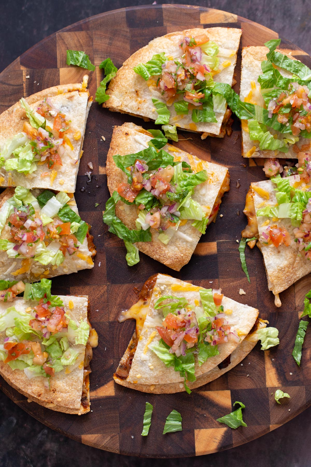 vegan mushroom quesadilla cut into wedges and topped with salsa and romaine served on a wooden board