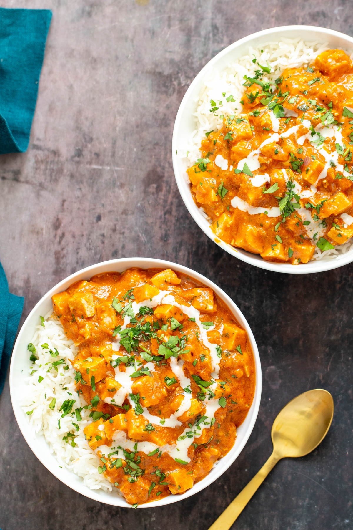 baked tofu curry two bowl with Indian vegan baked tofu curry served over fluffy rice with a golden spoon on the side