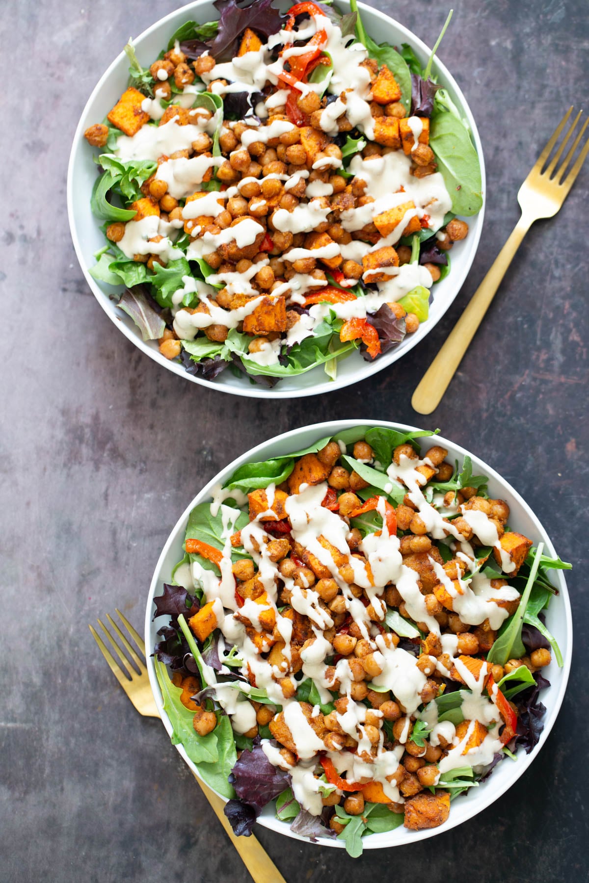 sweet potato salad sweet potato chickpea salad served in two white bowls drizzled with tahini dressing