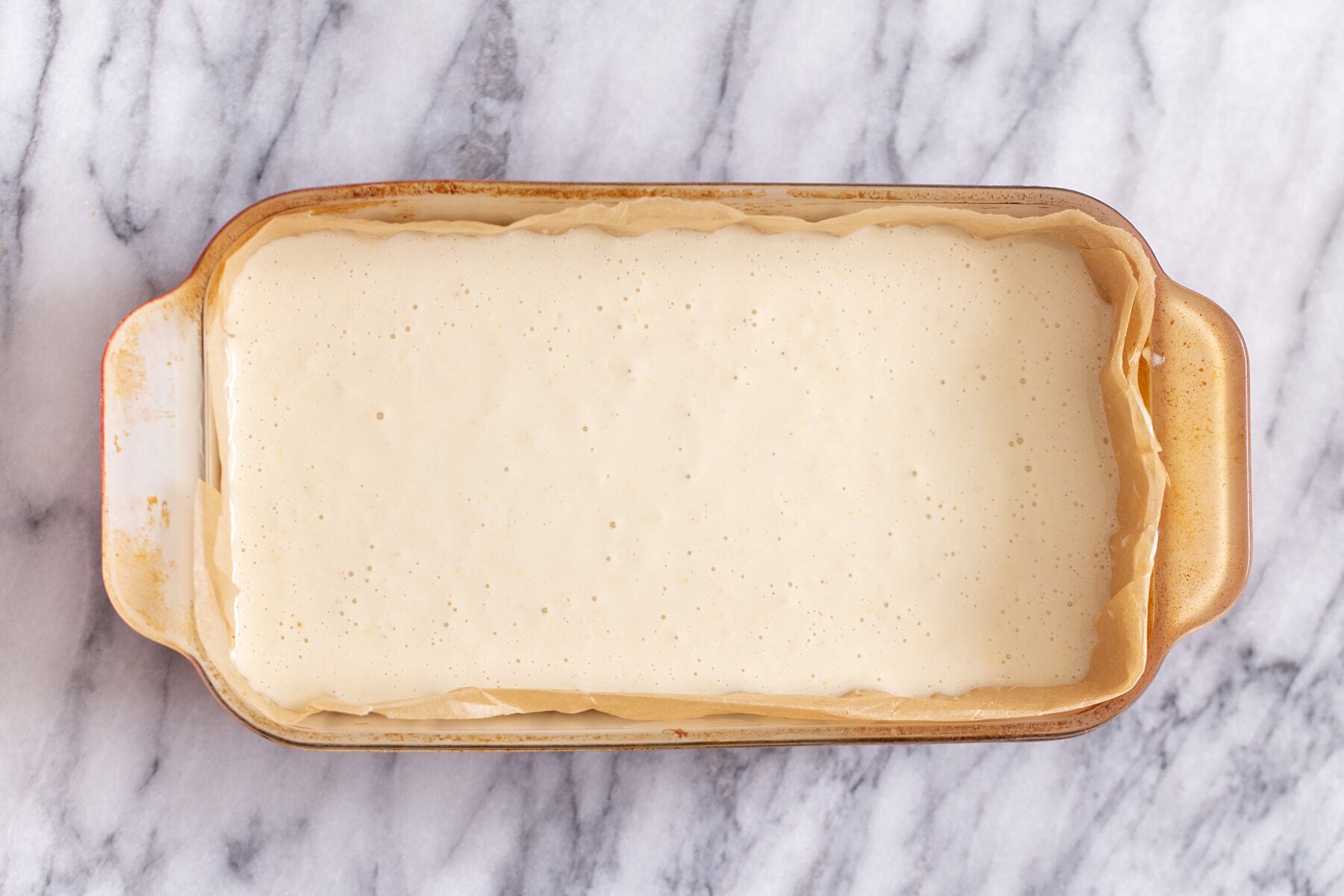vegan lemon bars vegan lemon cream filling being poured in a pyrex loaf pan to make lemon bars