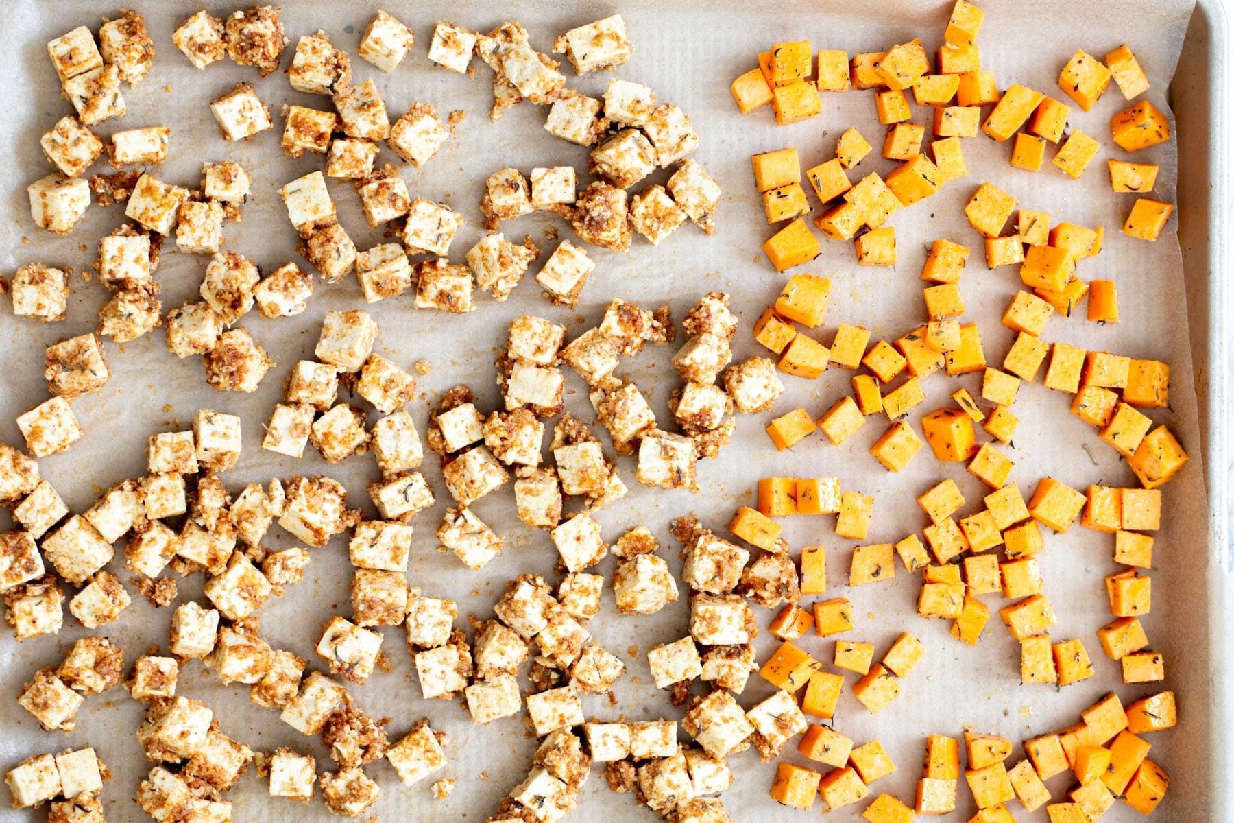 tofu and sweet potato cubes on a baking sheet ready to be baked