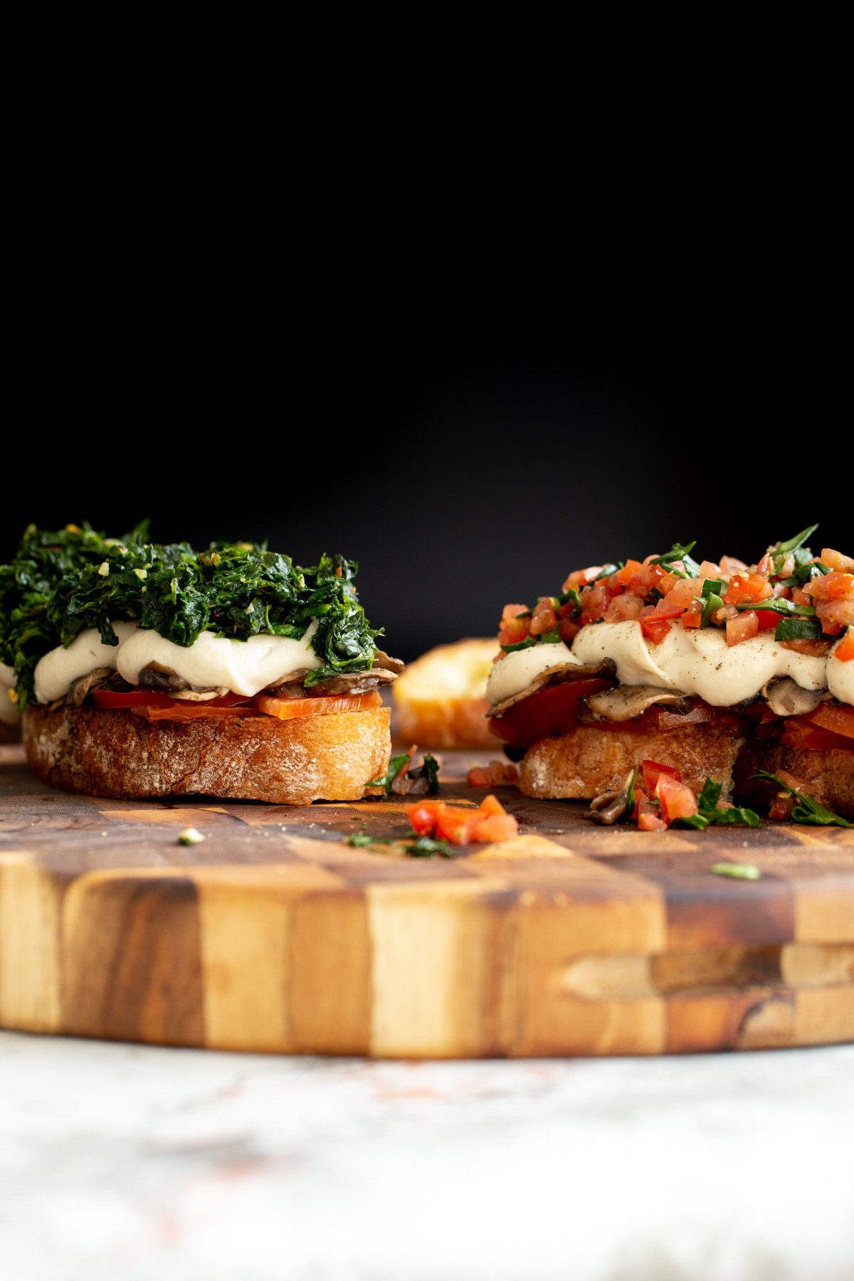 vegan cheese melts side view of vegan cheese melts topped with spinach and chopped tomatoes