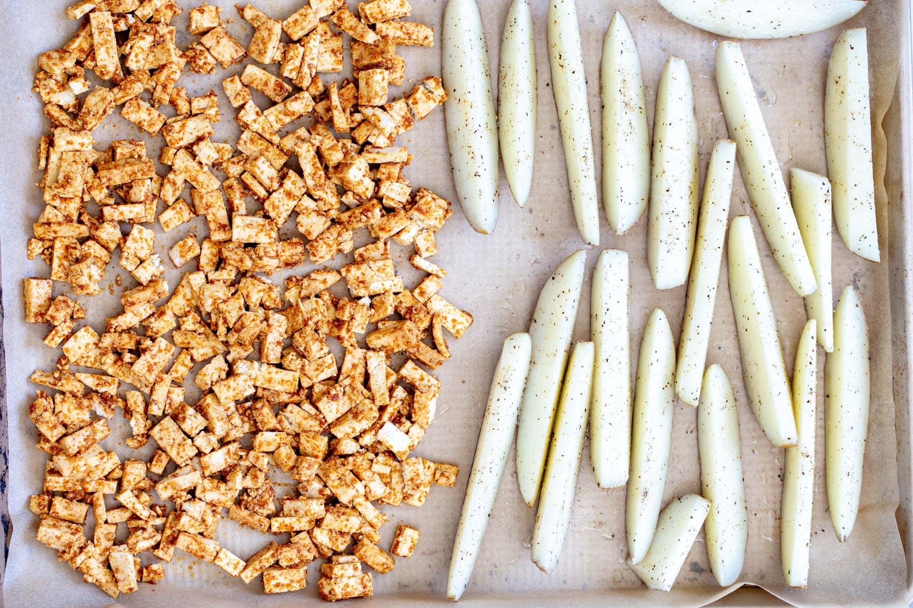 loaded potato wedges baking sheet with marinated tofu cubes and seasoned potato wedges