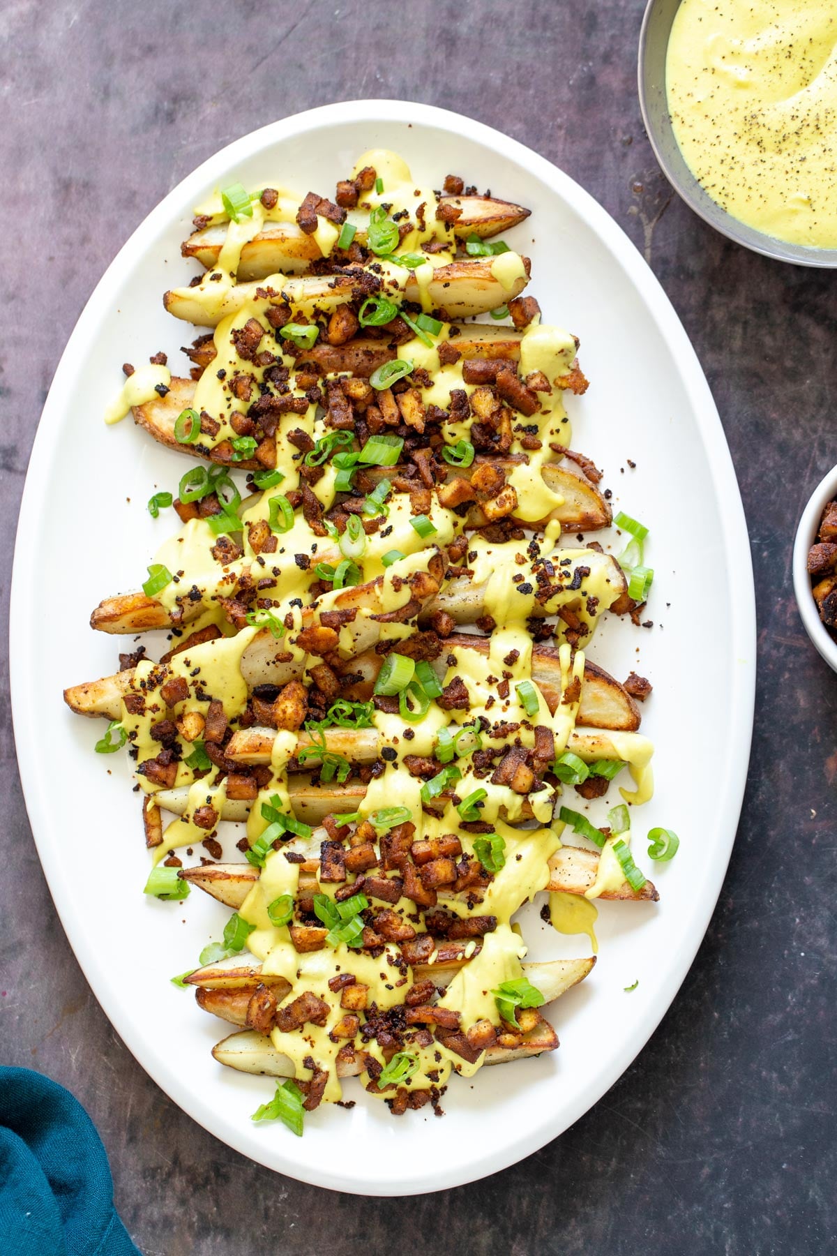 loaded potato wedges loaded baked potato wedges on a a platter topped with vegan cheese sauce and tofu bacon