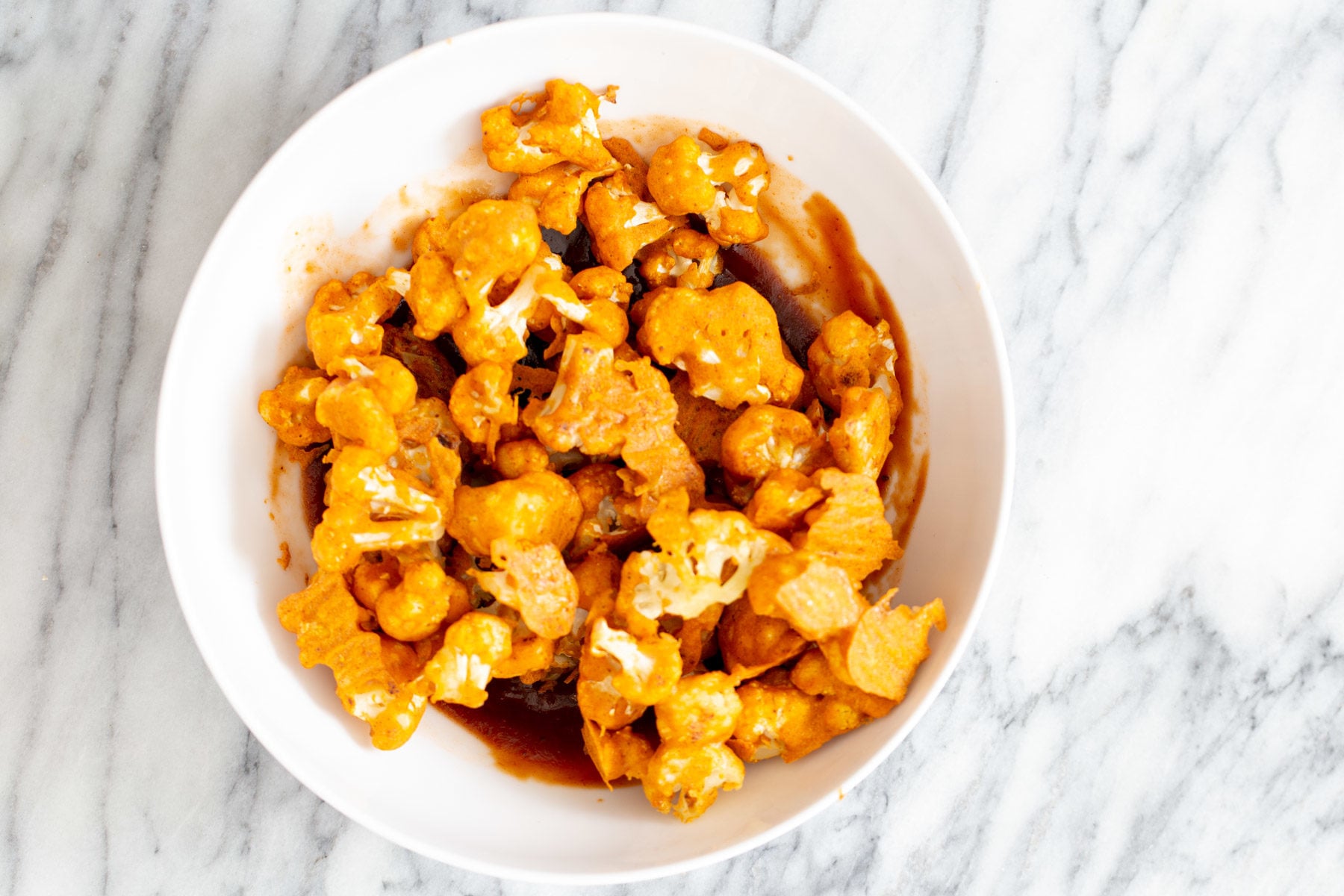 cauliflower wings beer battered baked cauliflower wings being tossed in hot sauce and bbq sauce