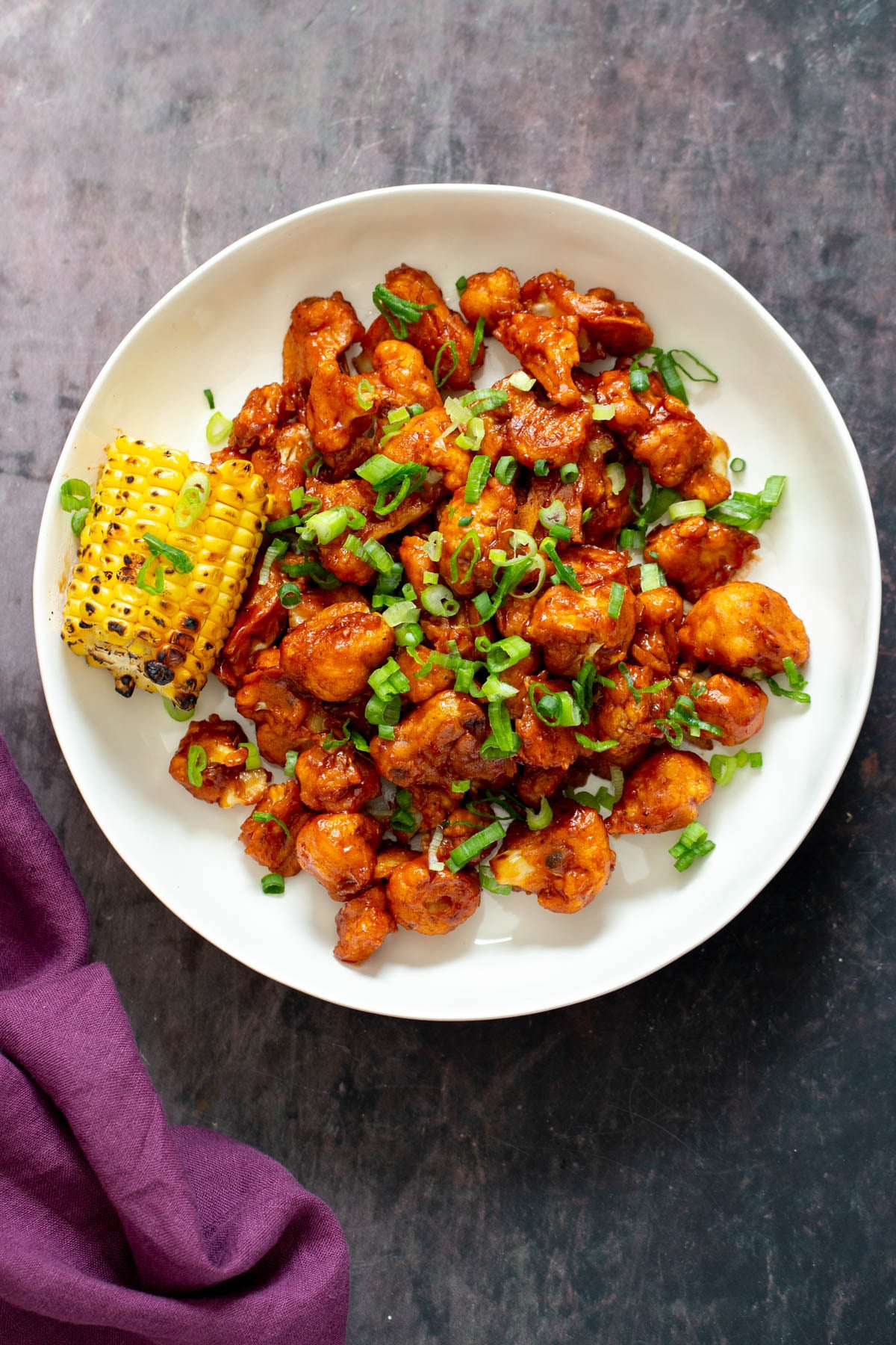 cauliflower wings vegan baked beet battered cauliflower wings coated in bbq sauce served on a white plate with corn on the cob