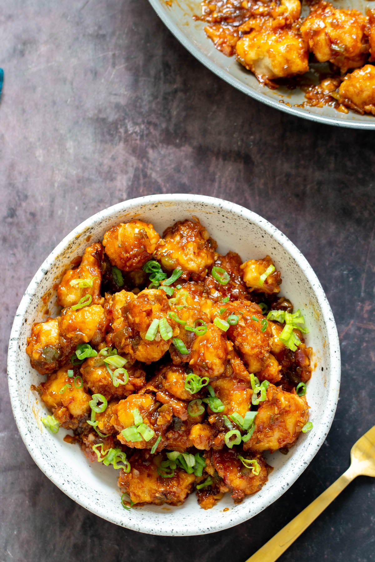 cauliflower manchurian a serving of cauliflower manchurian in a white bowl with a golden fork on the side