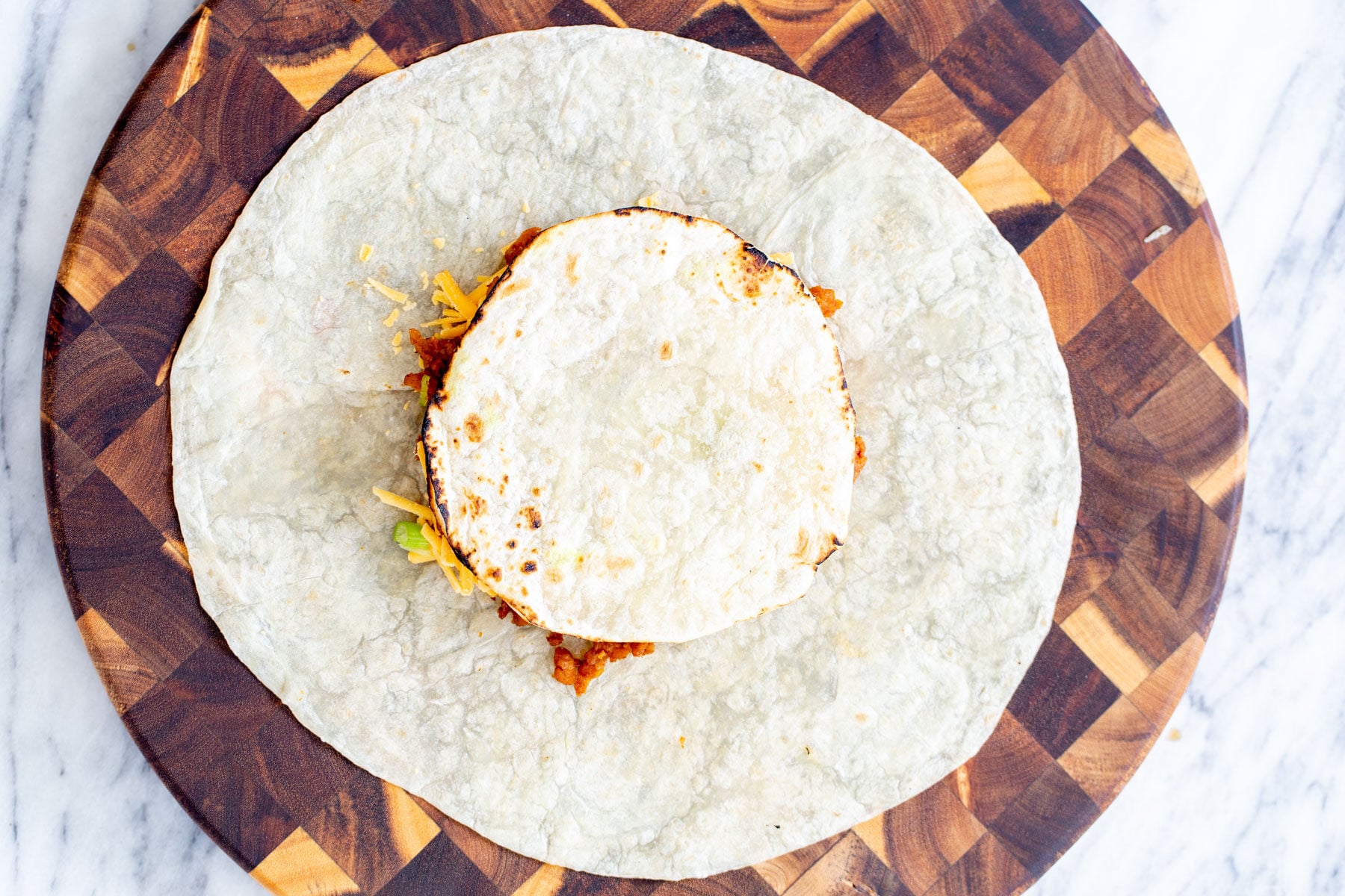 vegan crunchwrap a tostada being placed on toppings