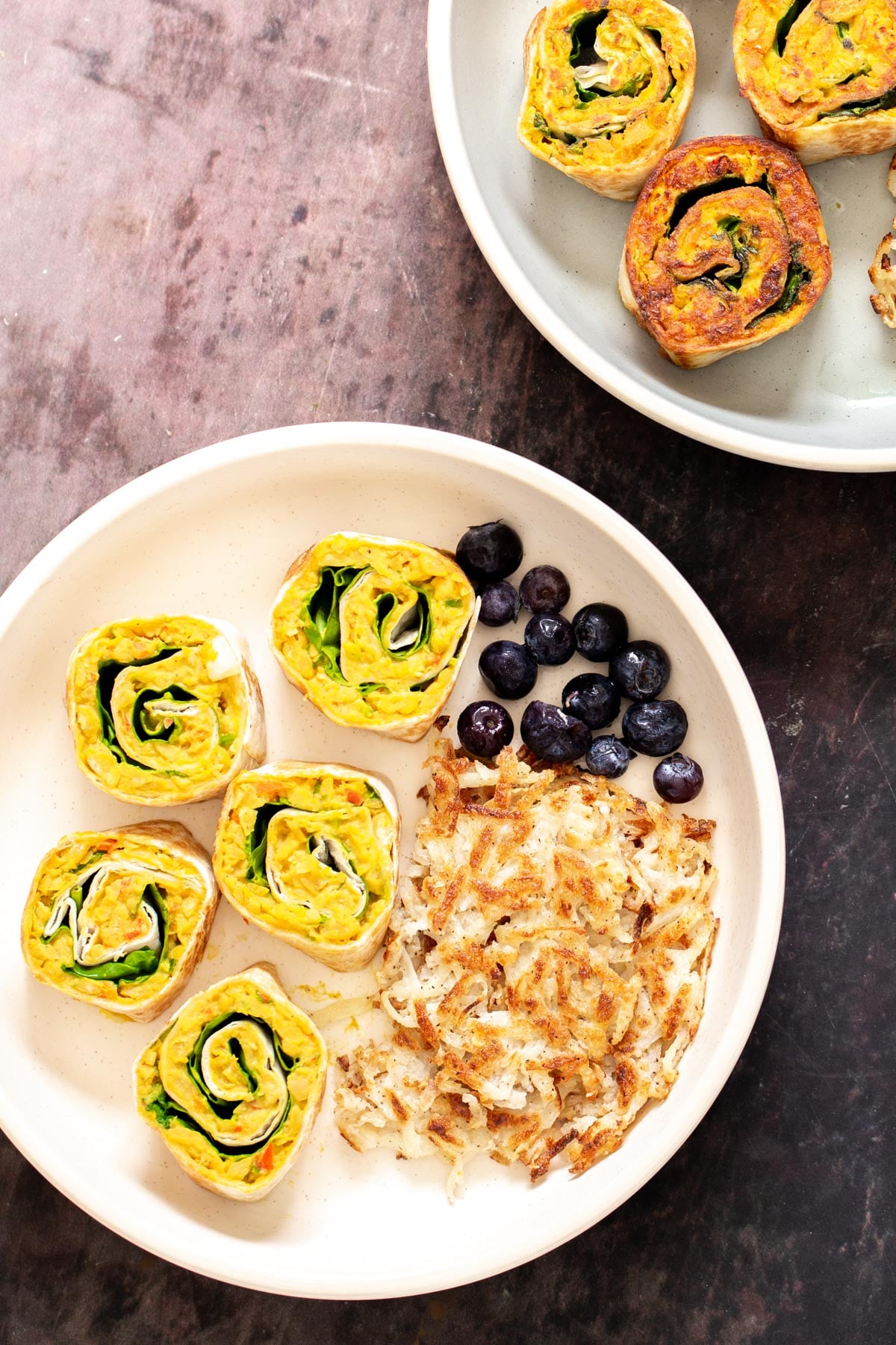 vegan chickpea breakfast platter with vegan chickpea scramble pinwheels, hash brown and berries 