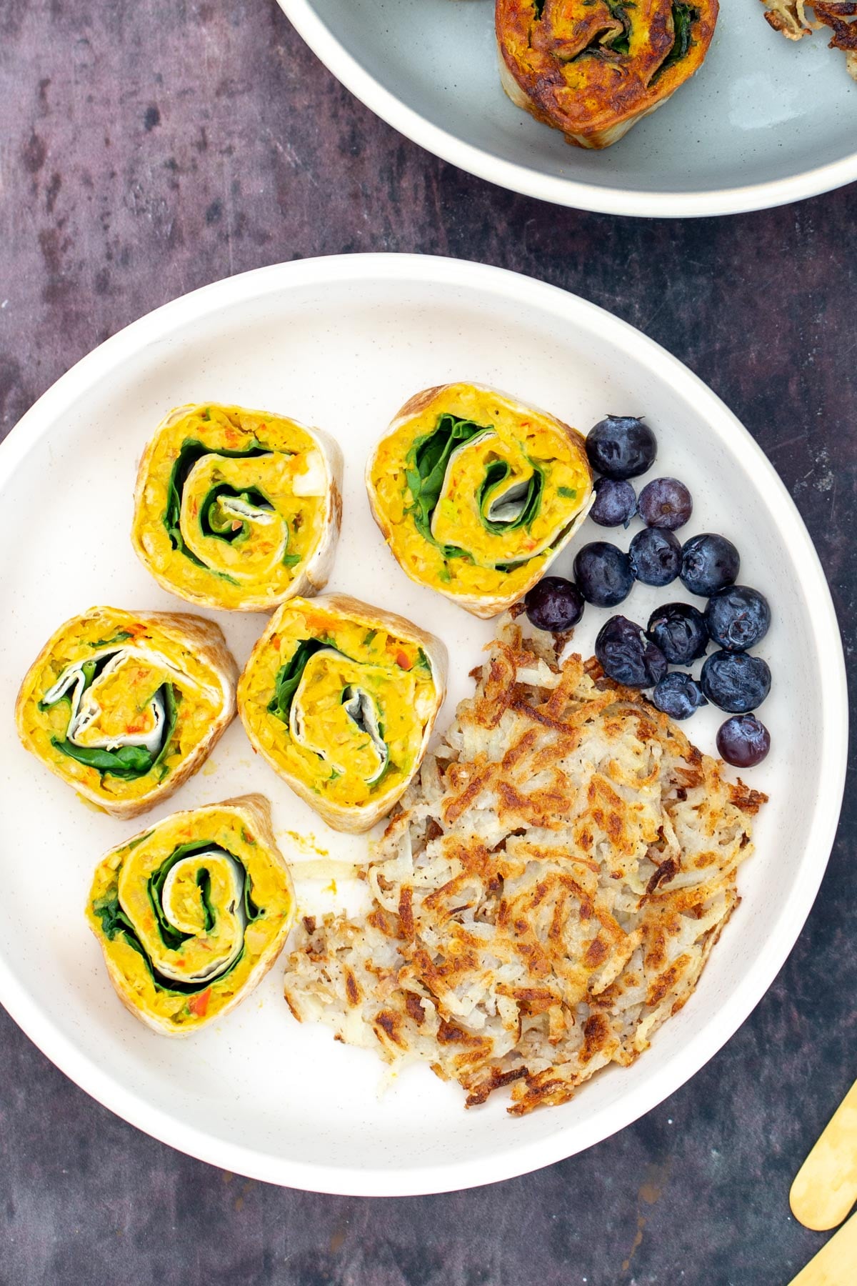 vegan chickpea breakfast rolls served on a plate with blueberries and hashbrowns 