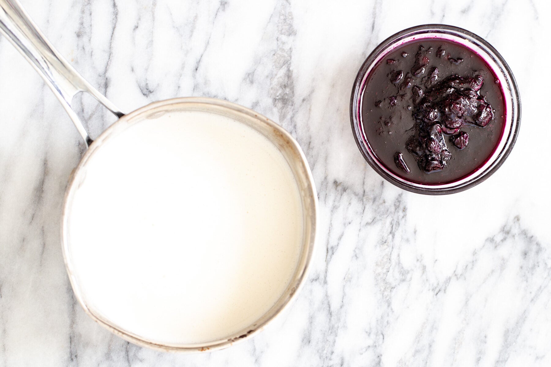 vanilla ice cream sandwiches a pot with vegan vanilla ice cream base next to a small dish with blueberry compote