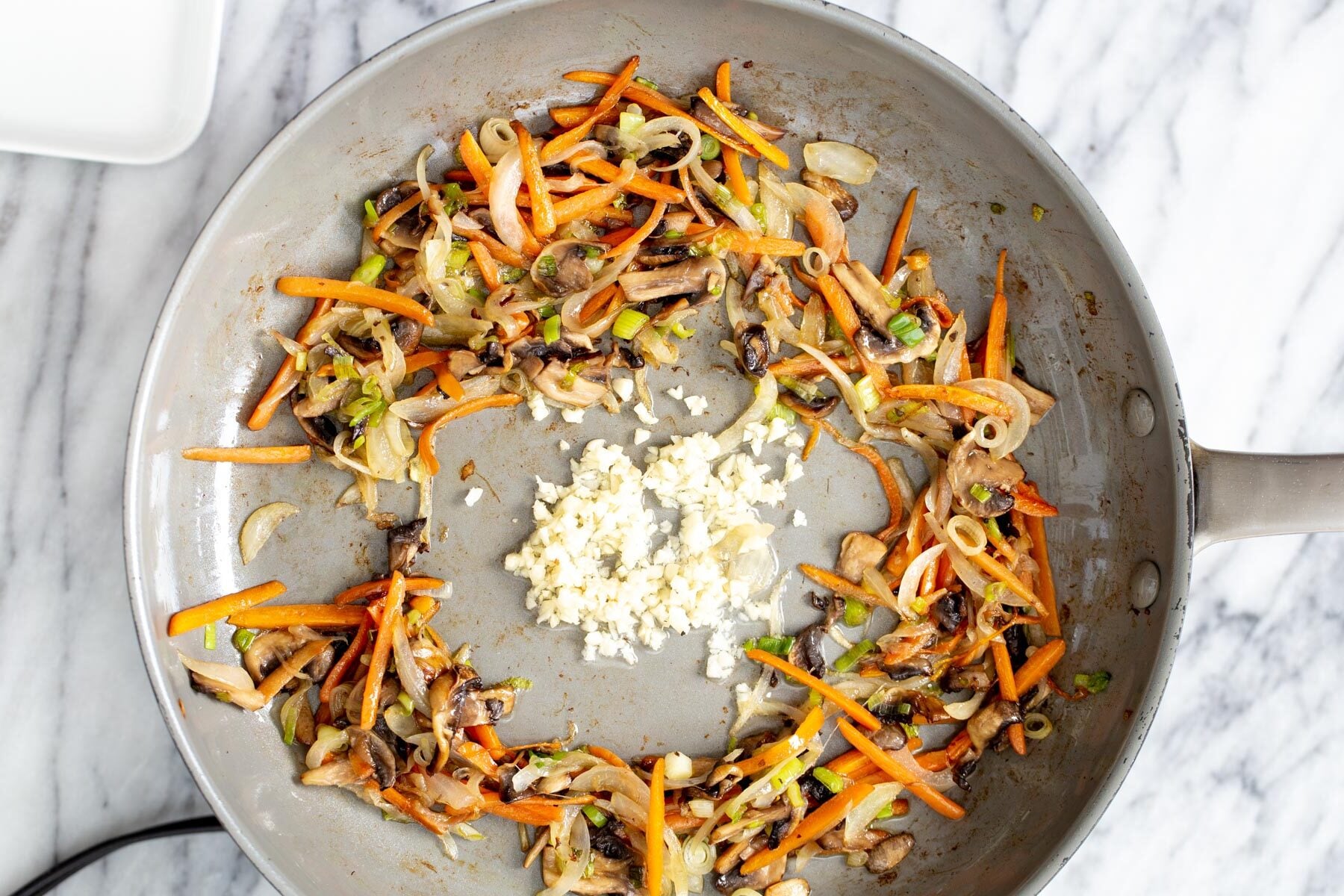 gochujang noodles finely sliced veggies stir-frying with garlic in a saucepan
