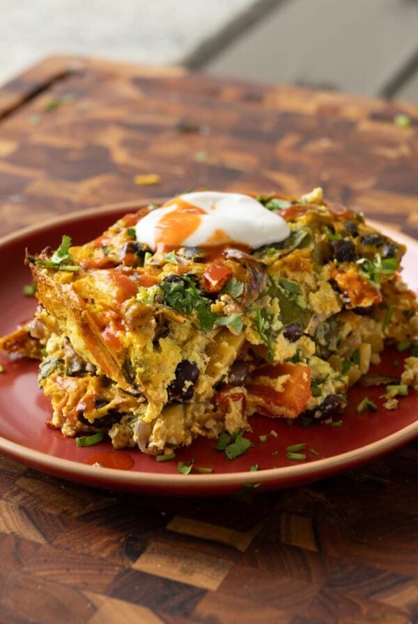 Mexican egg casserole on the plate topped with vegan sour cream and hot sauce