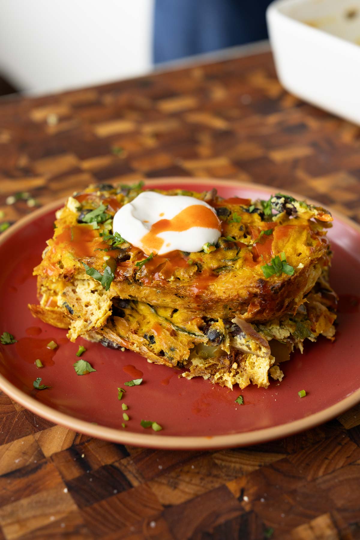 Mexican egg casserole on the plate topped with vegan sour cream and hot sauce