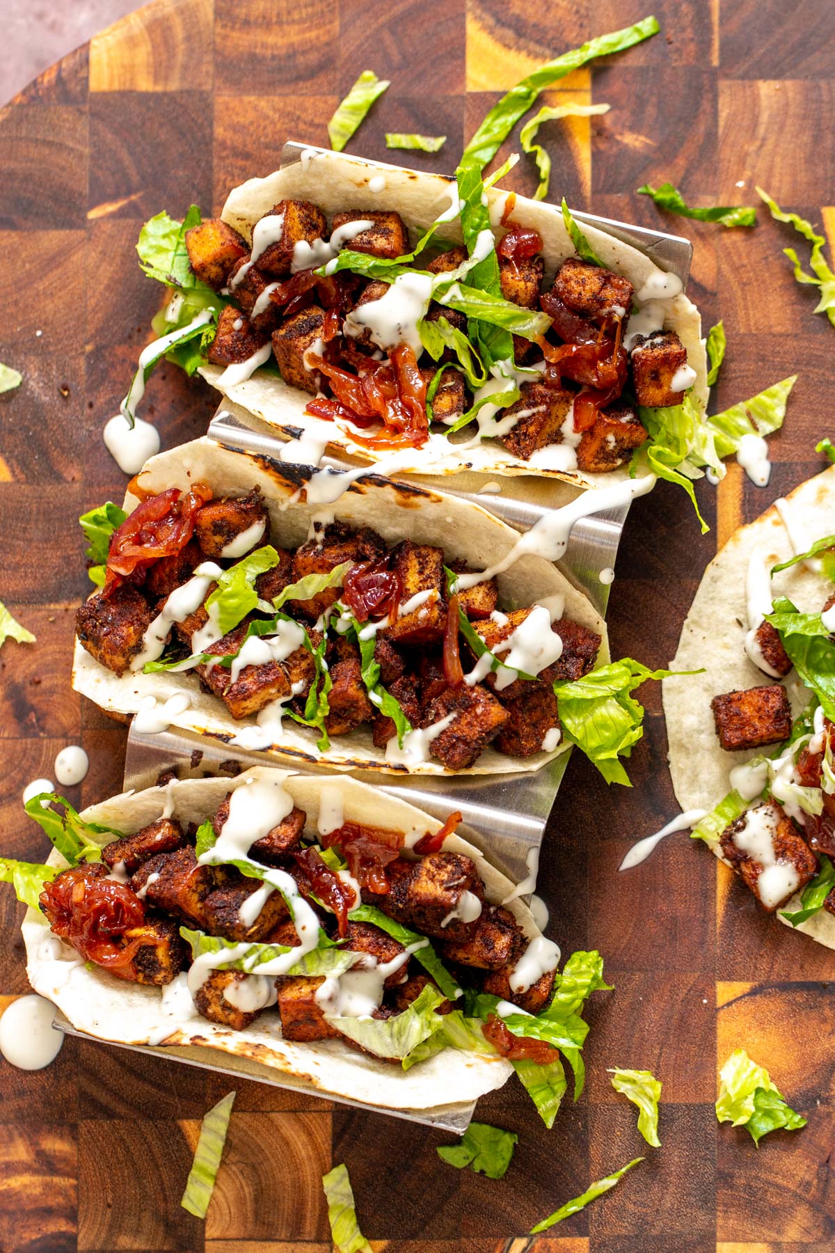 overhead shot of vegan blackened tofu tacos drizzled with vegan sour cream