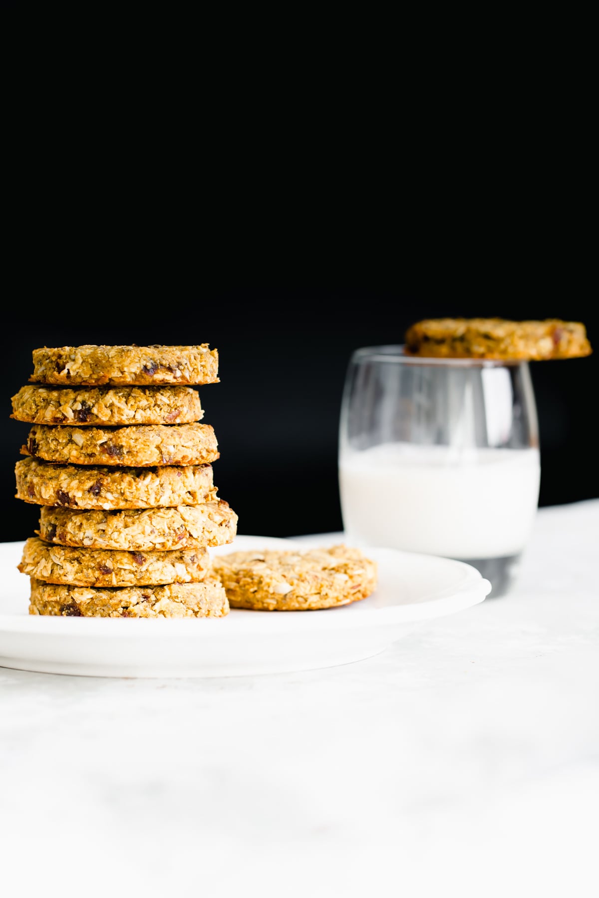 pumpkin breakfast cookies stacked pumpkin breakfast cookies on a white plate with a glass of milk in the background