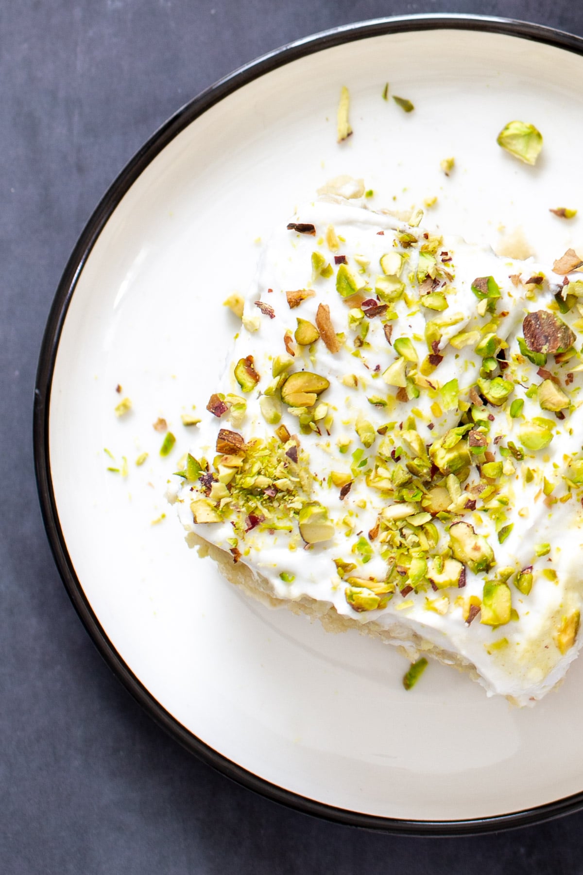 vegan tres leches a slice of vegan ras malai tres leches sprinkled with pistachios served on a white plate
