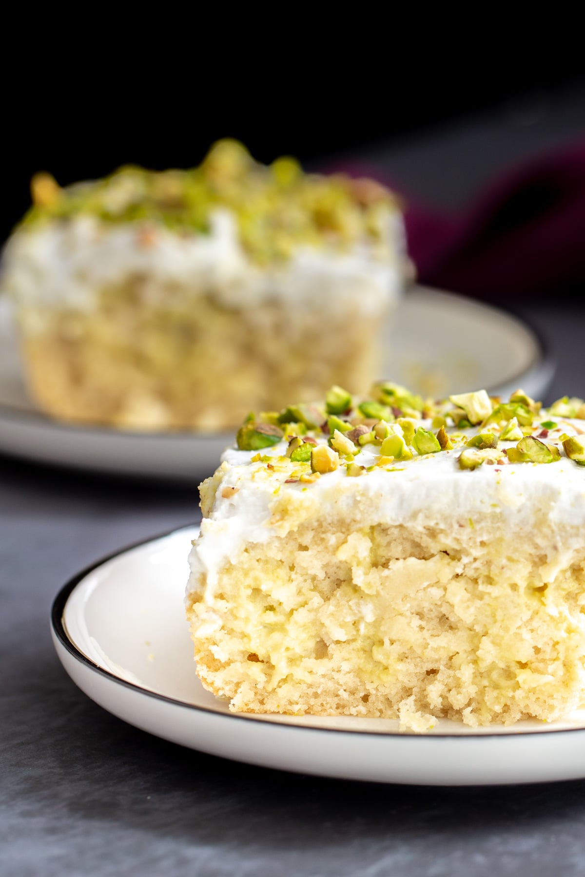 vegan tres leches side view of a slice of vegan tres leches cake sprinkled with pistachios