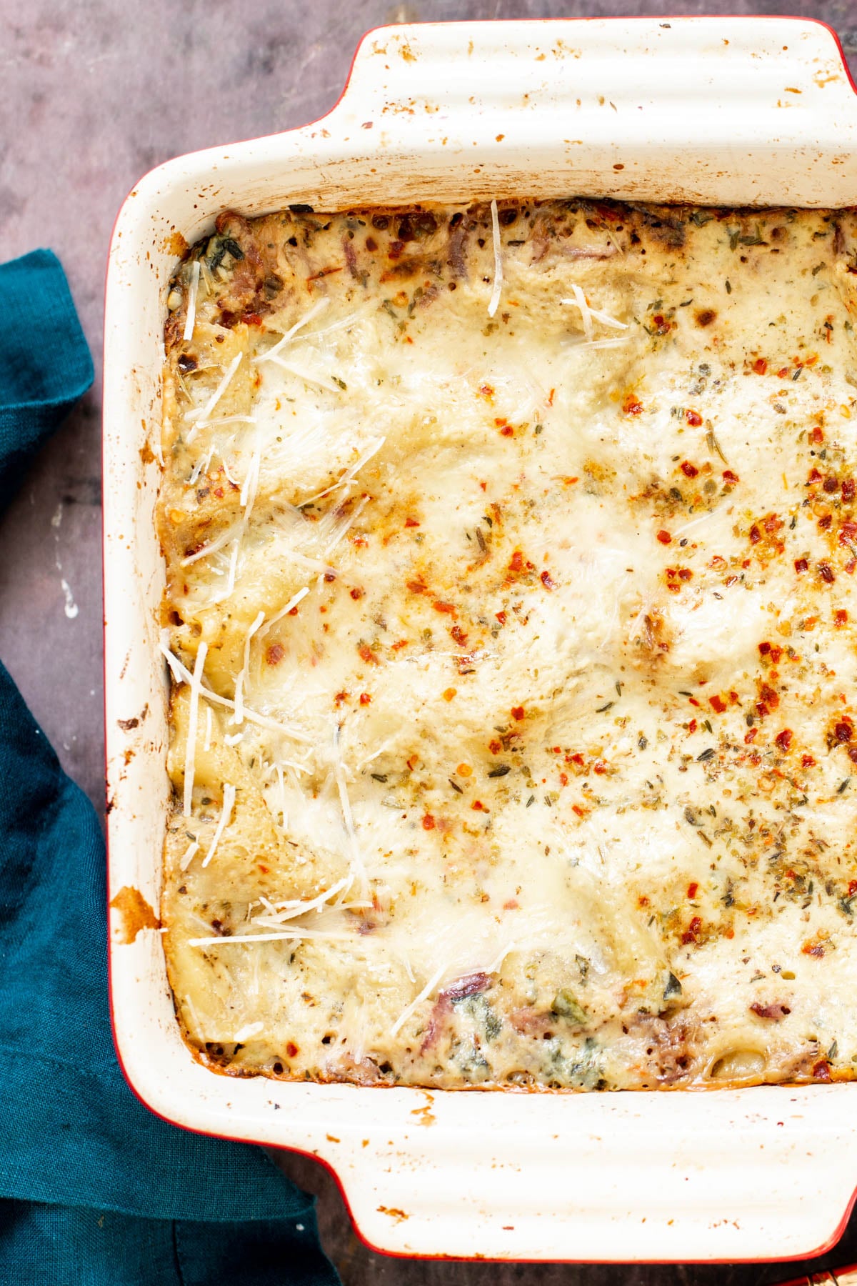 a casserole dish with vegan butternut squash lasagna topped with red pepper flakes 