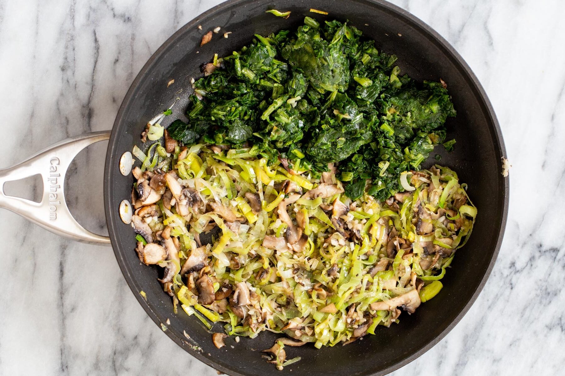 sauteed spinach mushrooms and leeks in a sauteeing pan