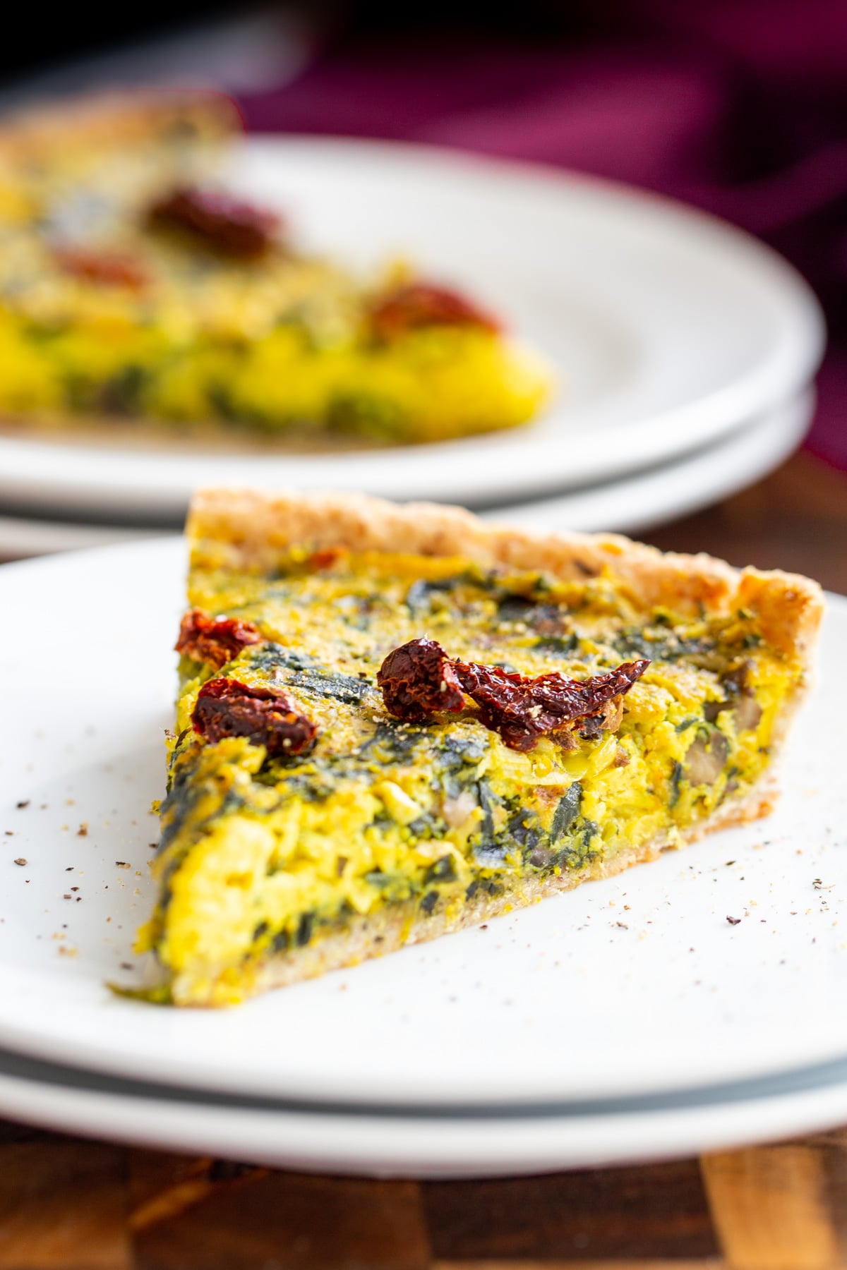 a slice of vegan quiche on a white plate