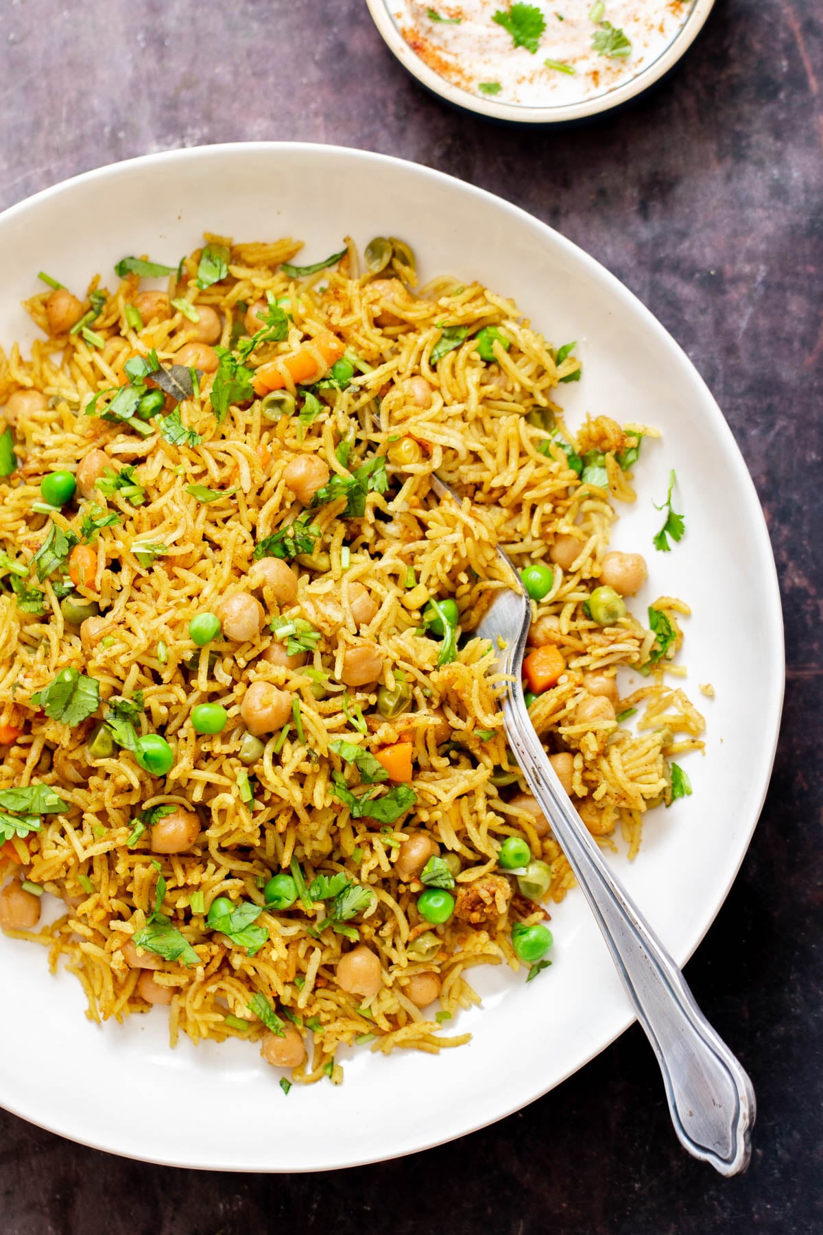 a plate of Instant Pot Curried Chickpea Fried Rice with peas served with a silver spoon